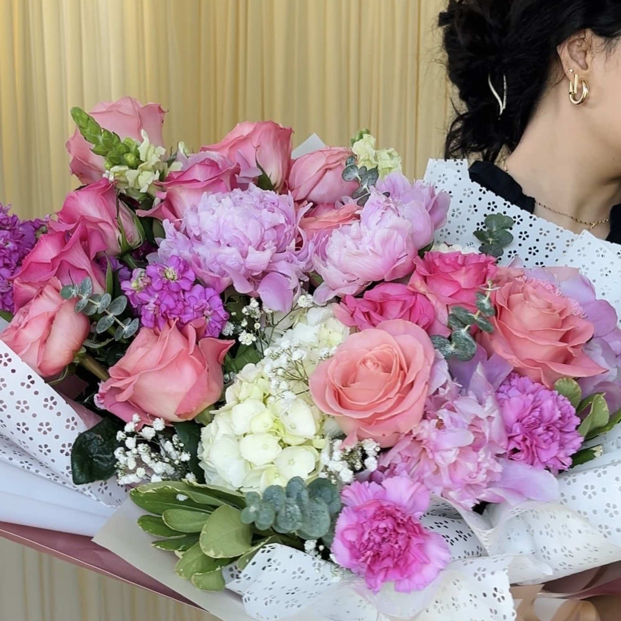 A lush, garden-style hand-tied bouquet overflowing with pink roses and layered peony-like