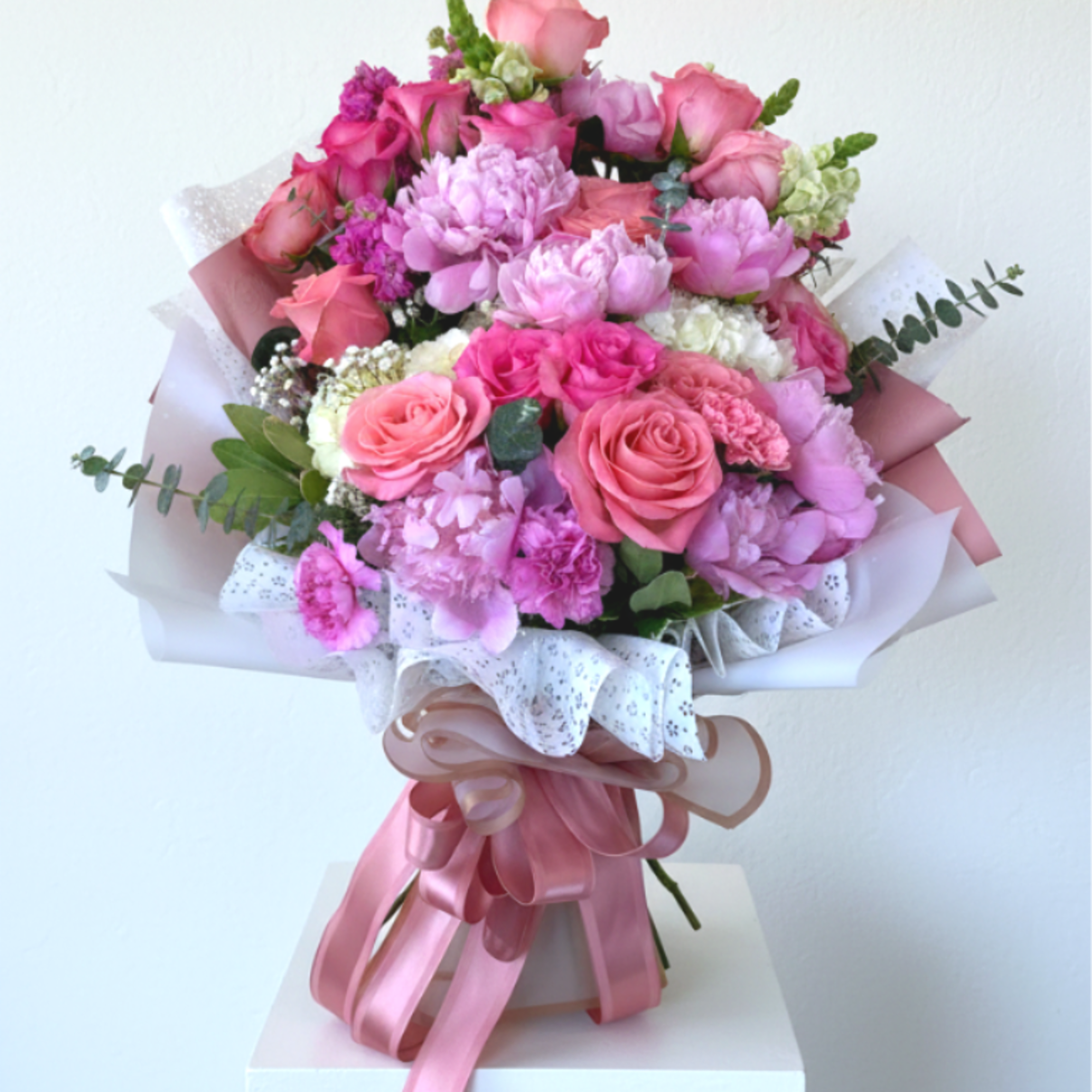 A lush, garden-style hand-tied bouquet overflowing with pink roses and layered peony-like