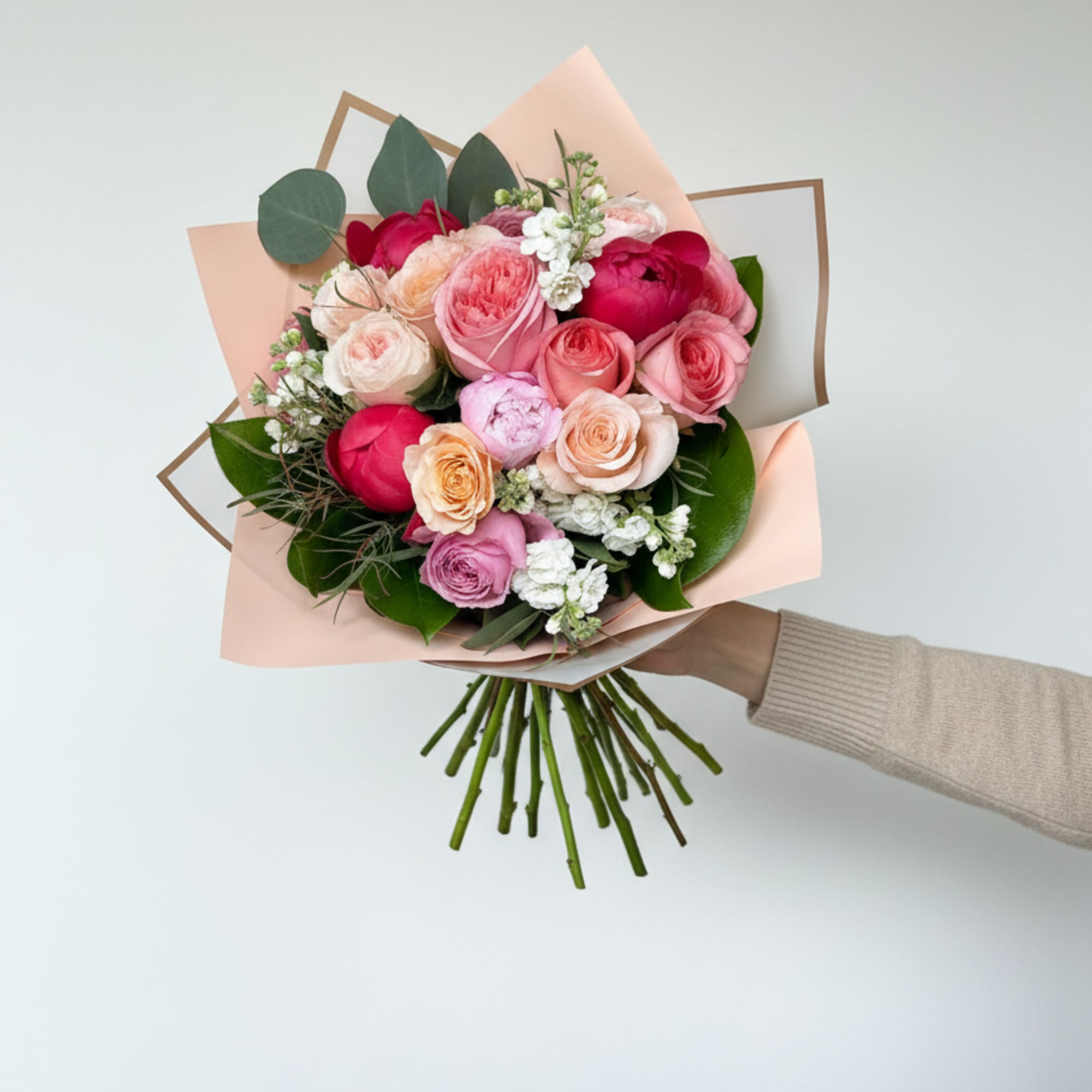 Layered roses in blush, peach, coral and deep pink form the heart