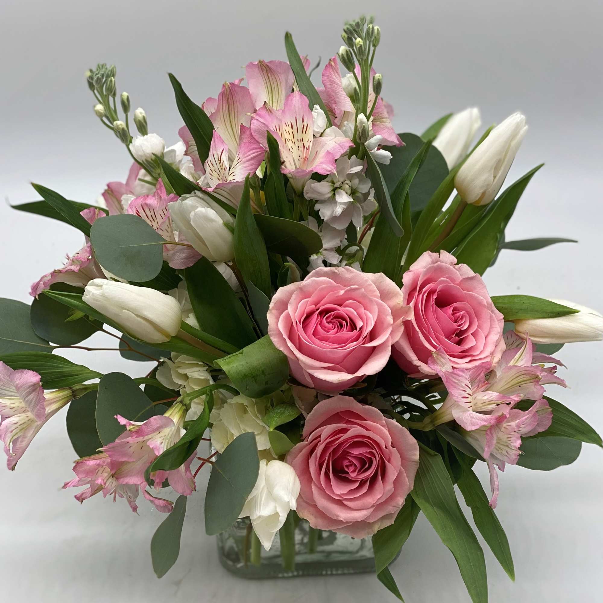 Pink roses and white tulips in a glass vase