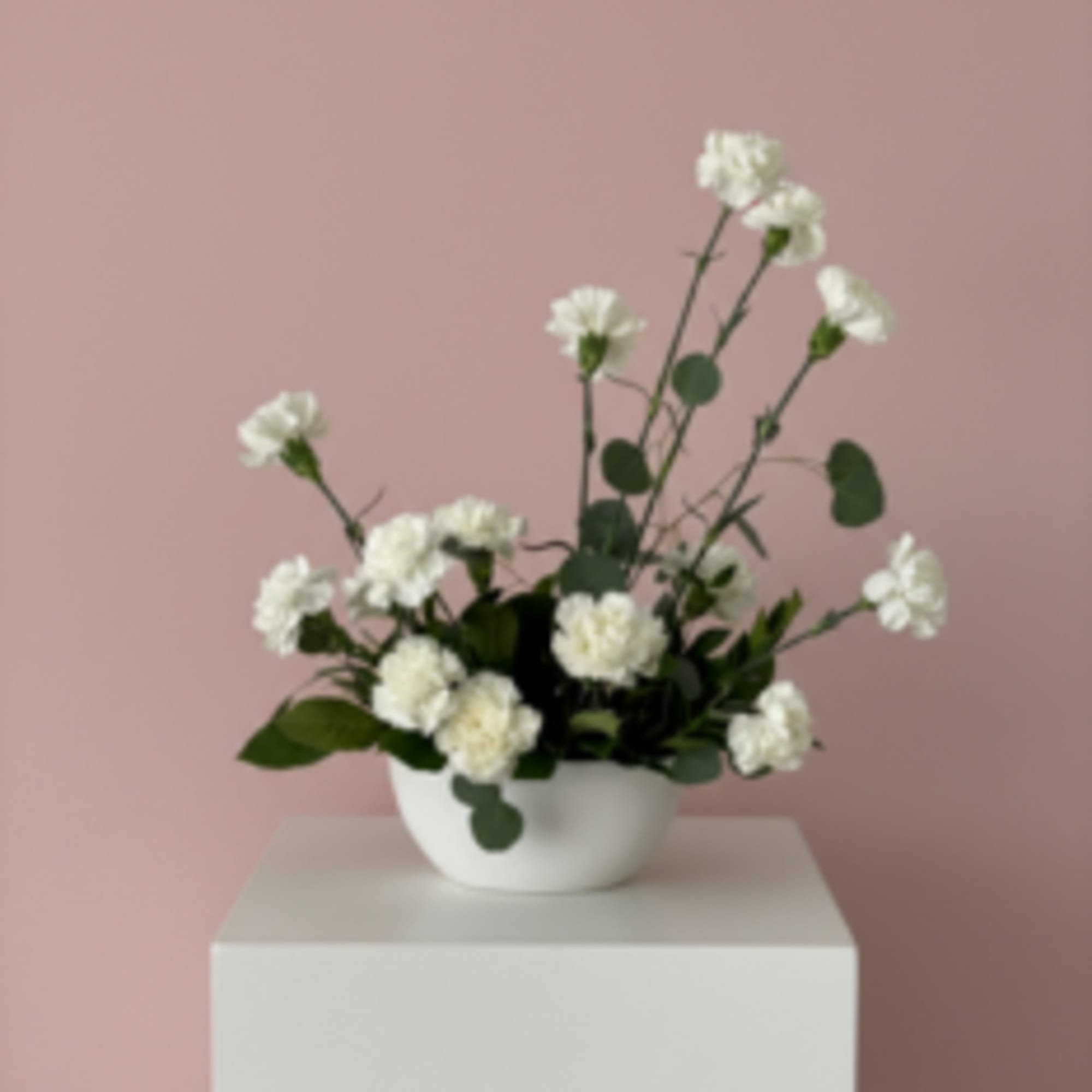 White carnations in a white bowl vase on a pedestal