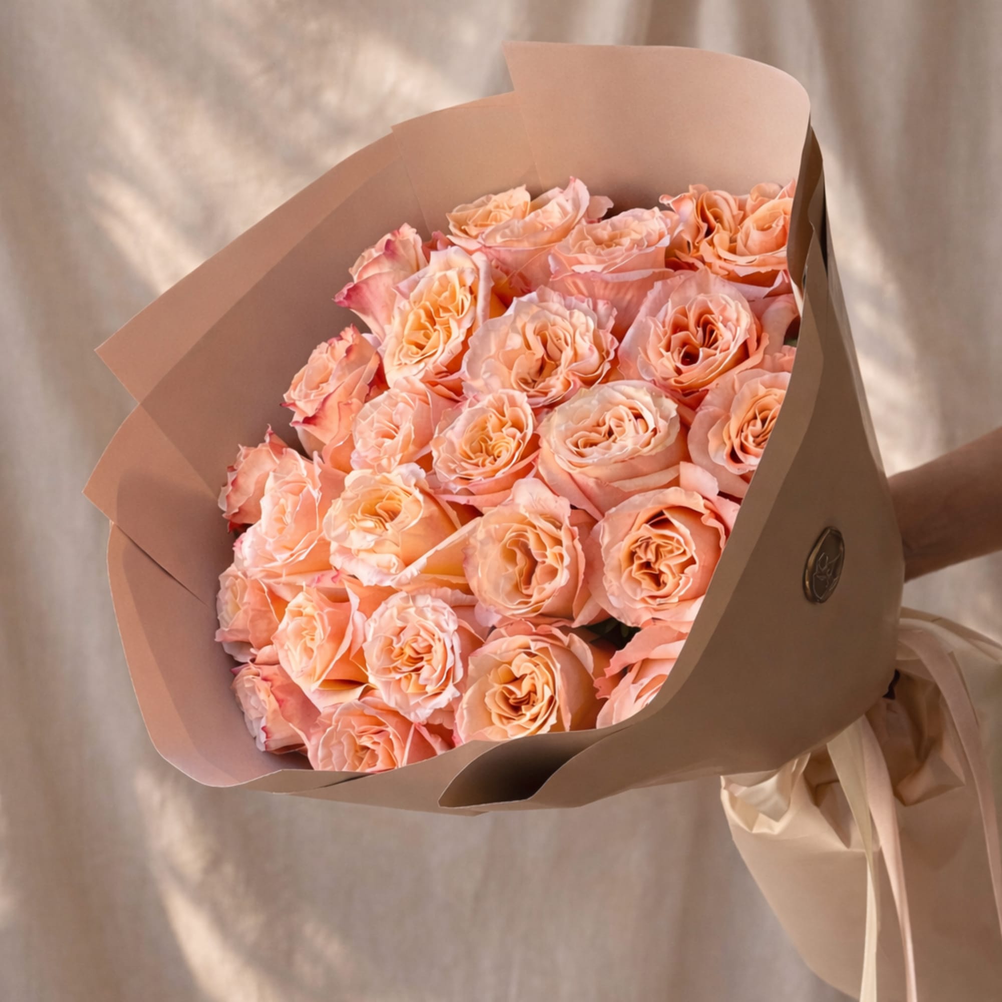 Bouquet of peach roses wrapped in beige paper