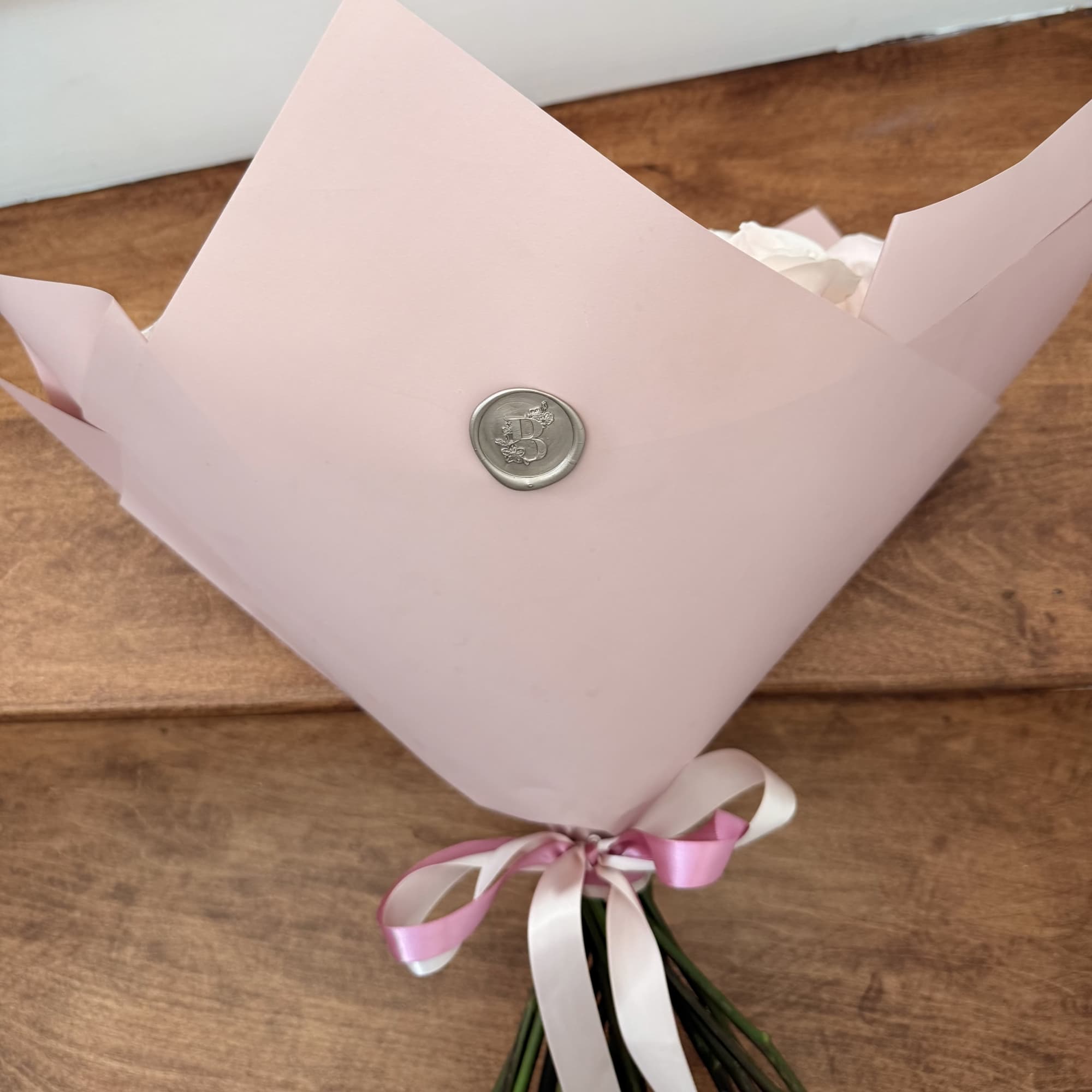Pink-wrapped bouquet tied with pink and white ribbon