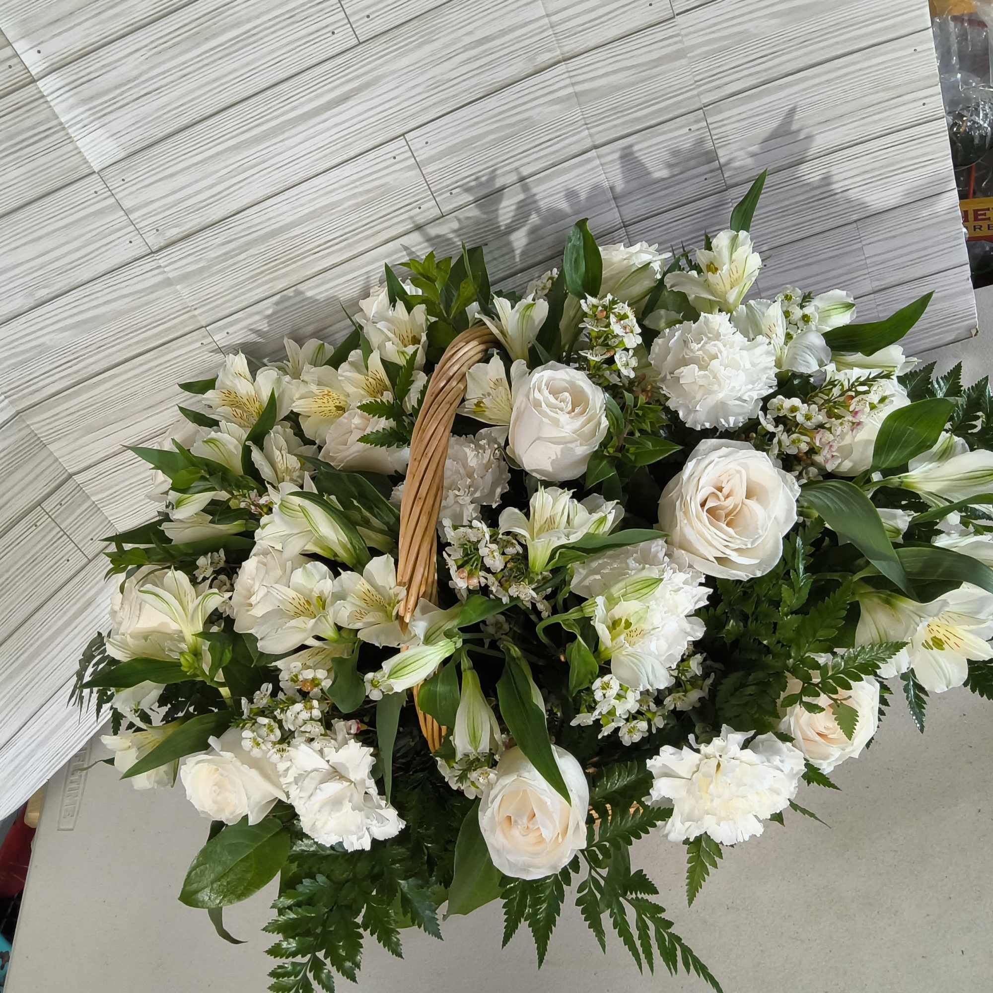 Basket arrangement of white roses and lilies with greenery