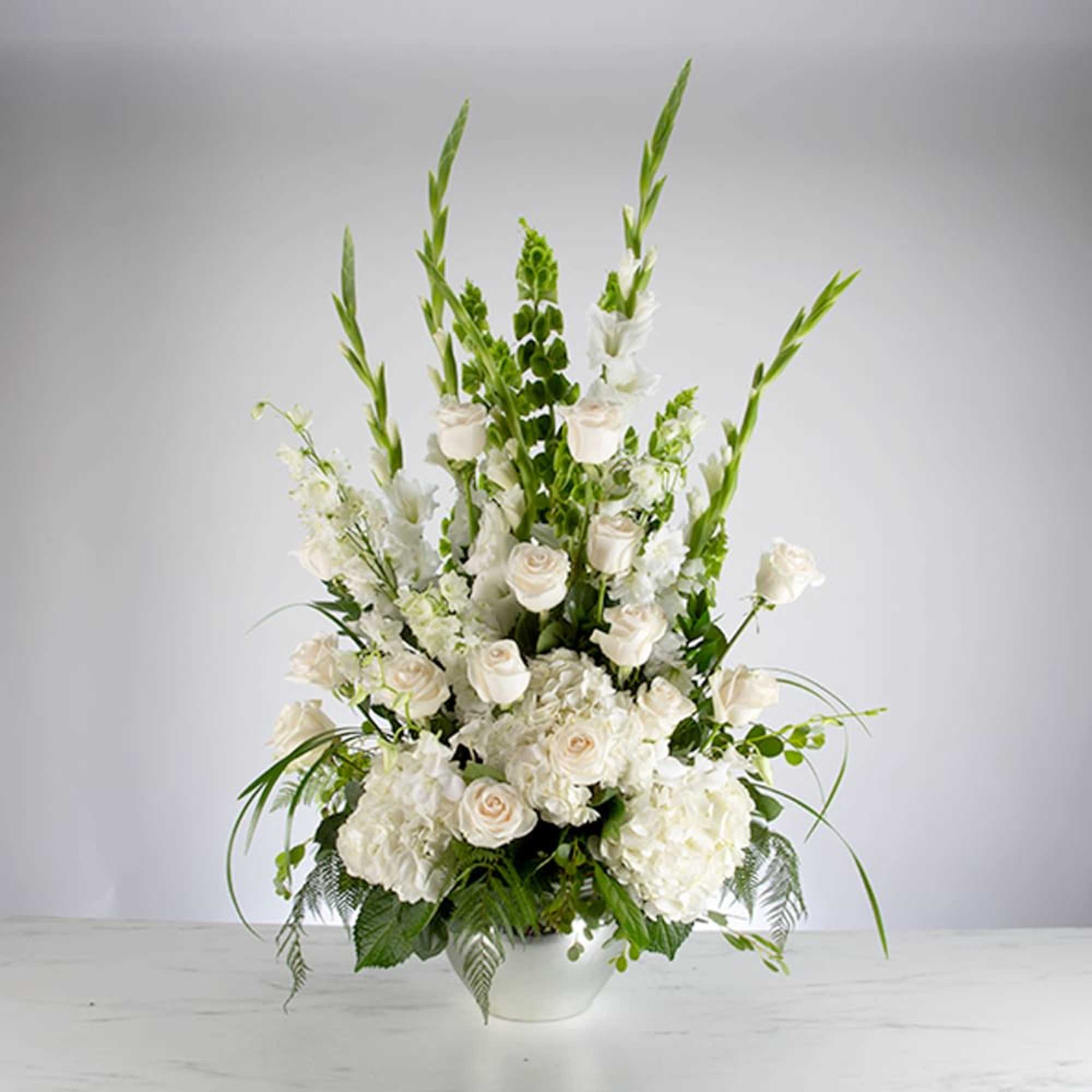 Tall white floral arrangement in a white bowl vase