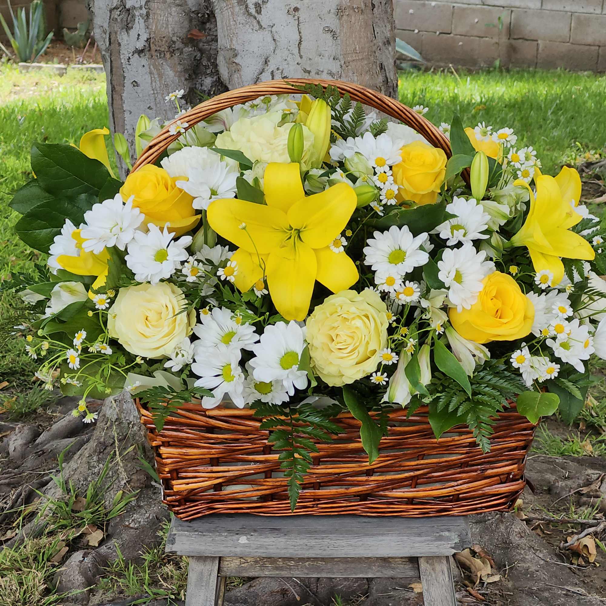 Basket arrangement of yellow lilies, roses, and white daisies