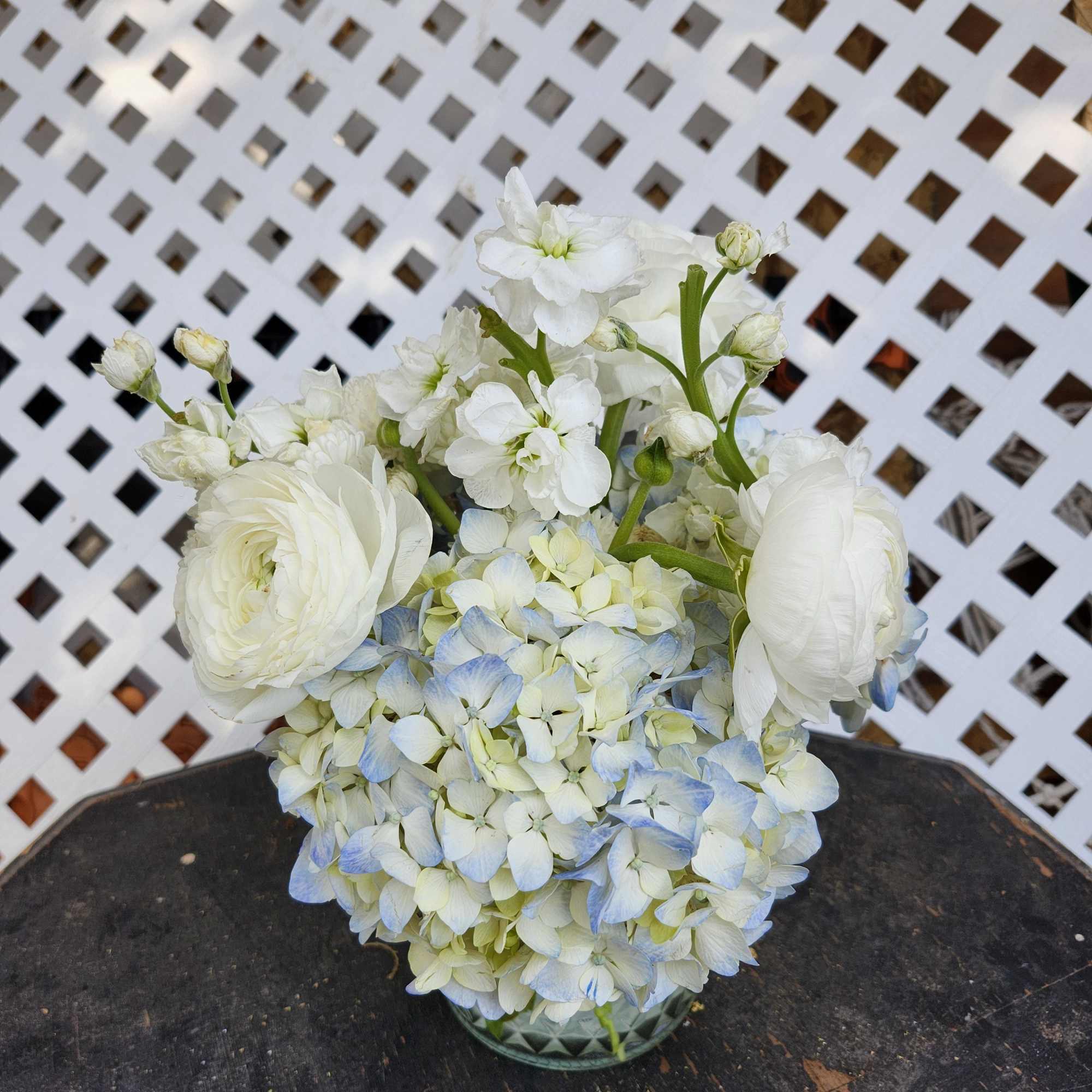 White and pale blue floral arrangement in a glass vase