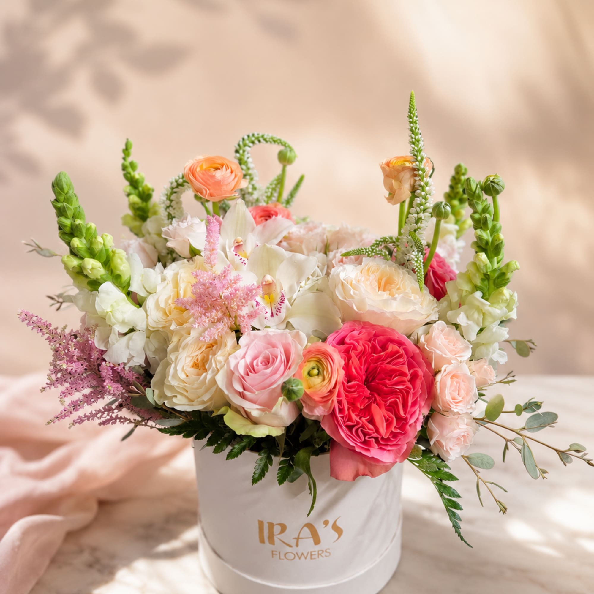 A white hatbox arrangement of white and pink flowers. Delicate just like