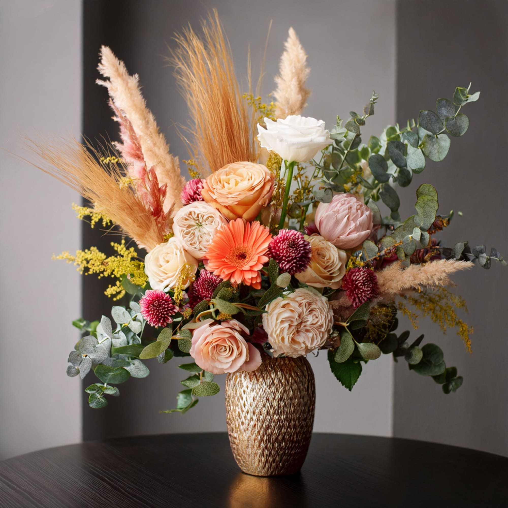 Mixed bouquet of peach, white, and pink flowers in a textured vase