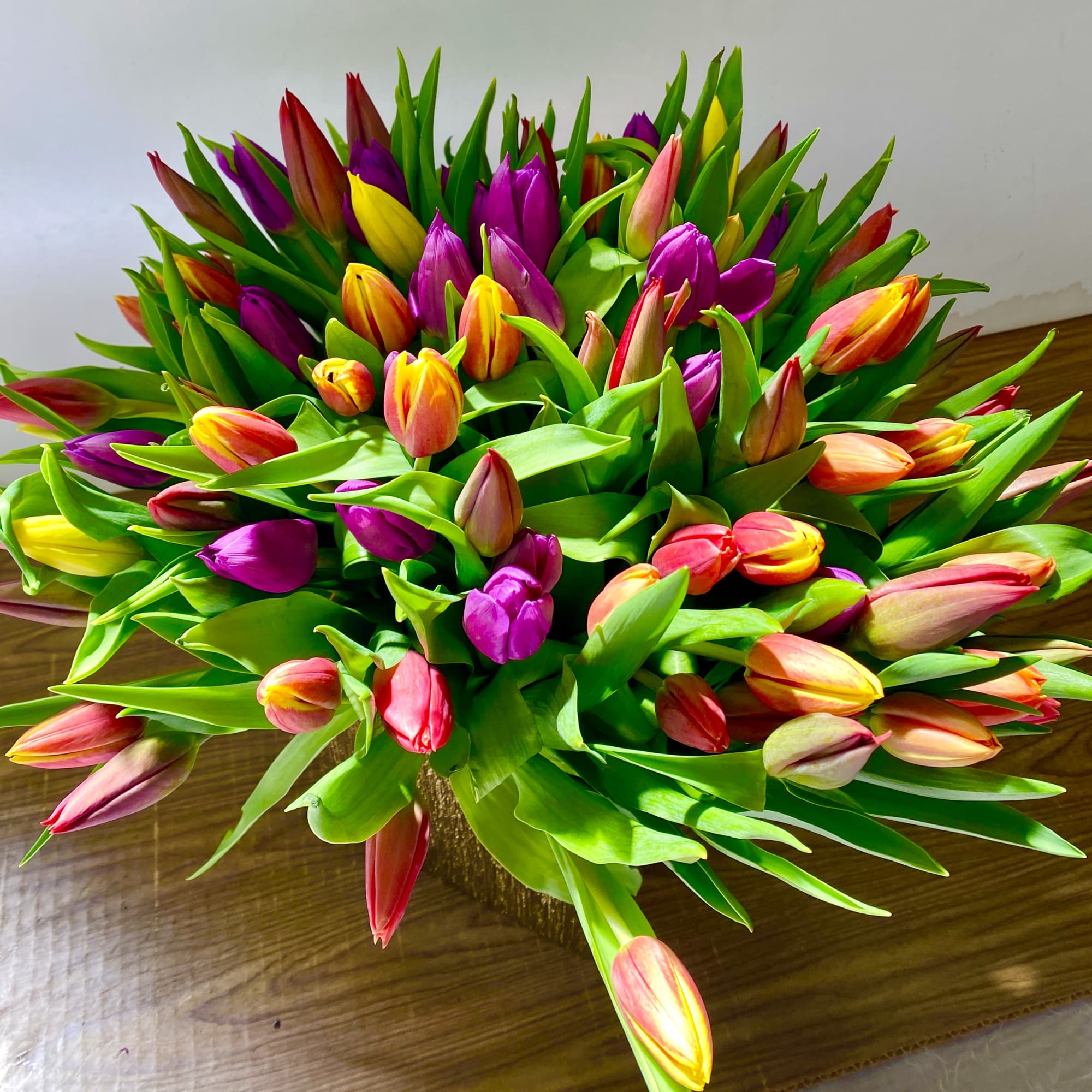 100 stems of different colors of tulips in a beautiful pink ceramics