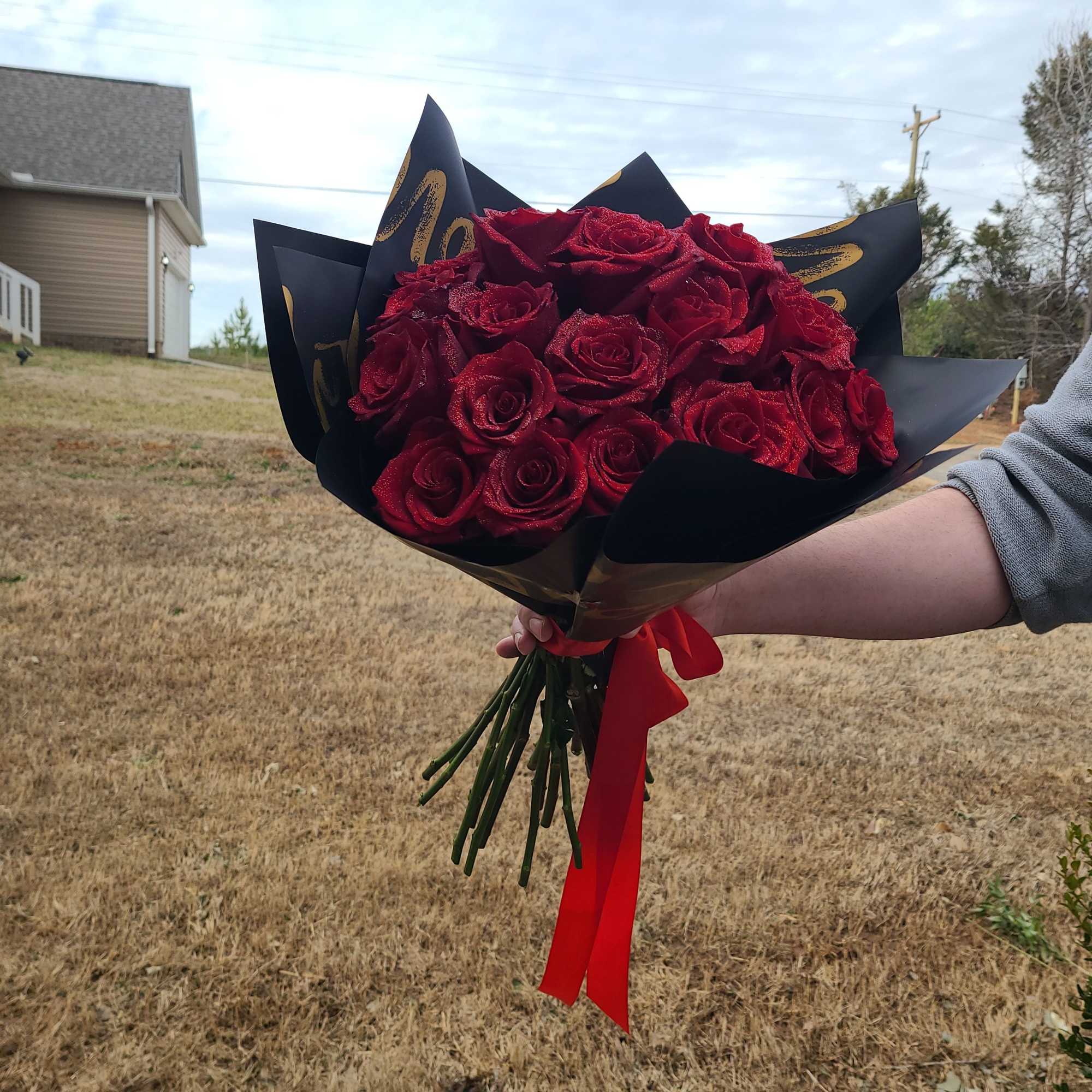 Bouquet of red roses wrapped in black paper with a red ribbon