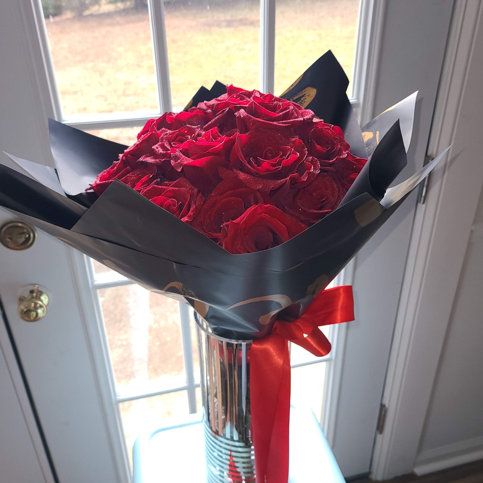 Bouquet of red roses wrapped in black paper with a red ribbon