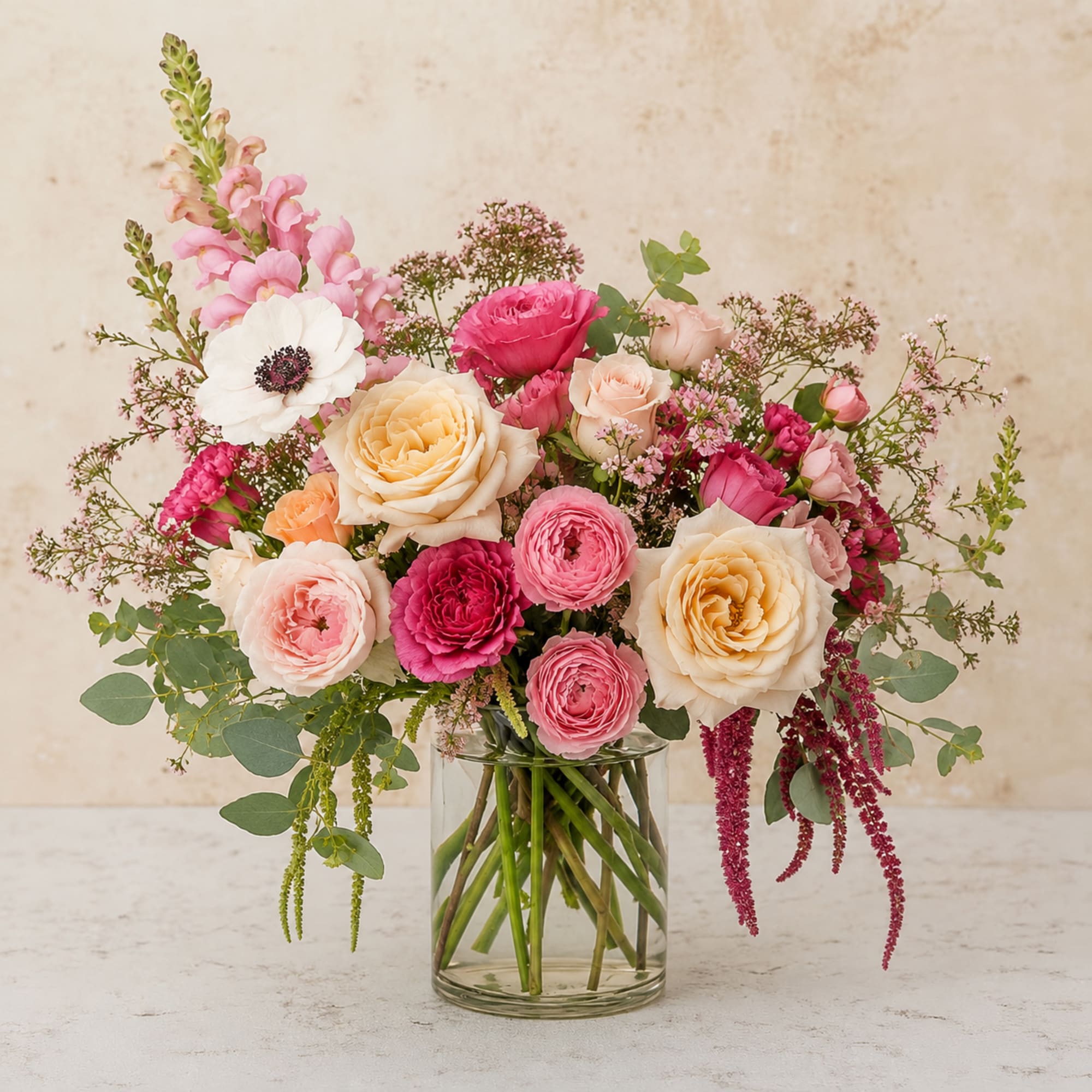 A graceful blend of blush-pink and peach garden roses, vibrant ranunculus, a