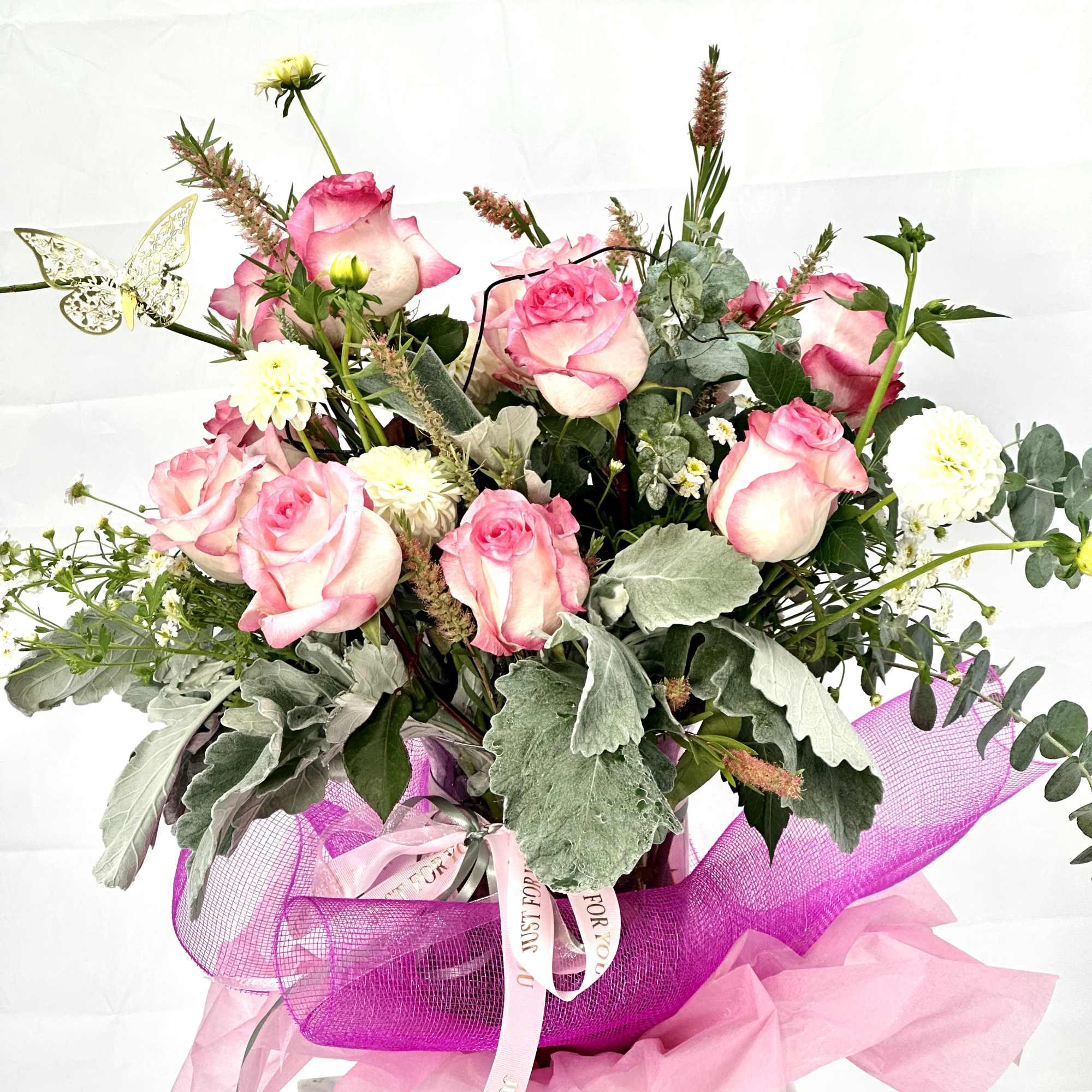 Pink roses arranged with white blooms in a wrapped bouquet