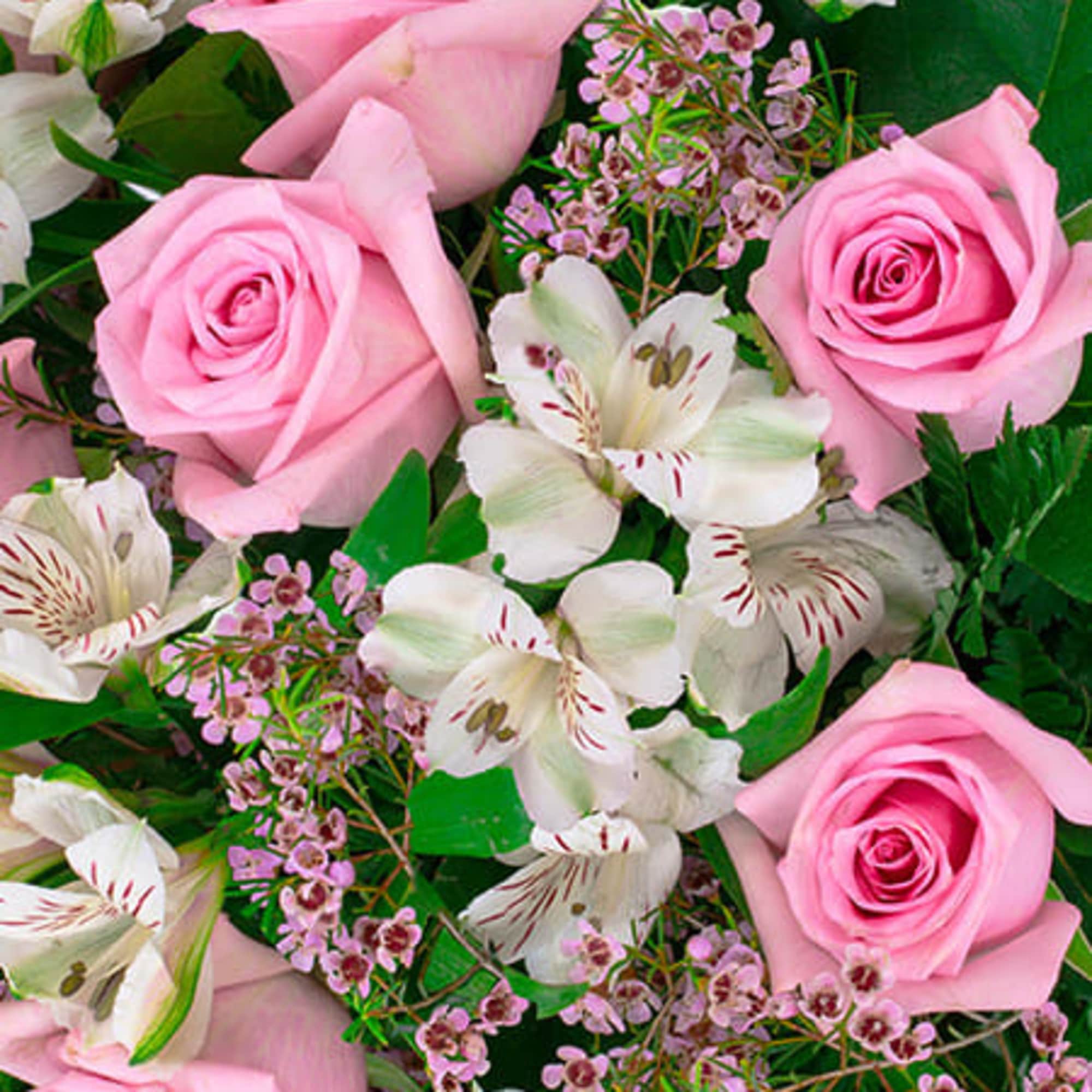 Close-up of pink roses mixed with white alstroemeria and tiny pink filler flowers.