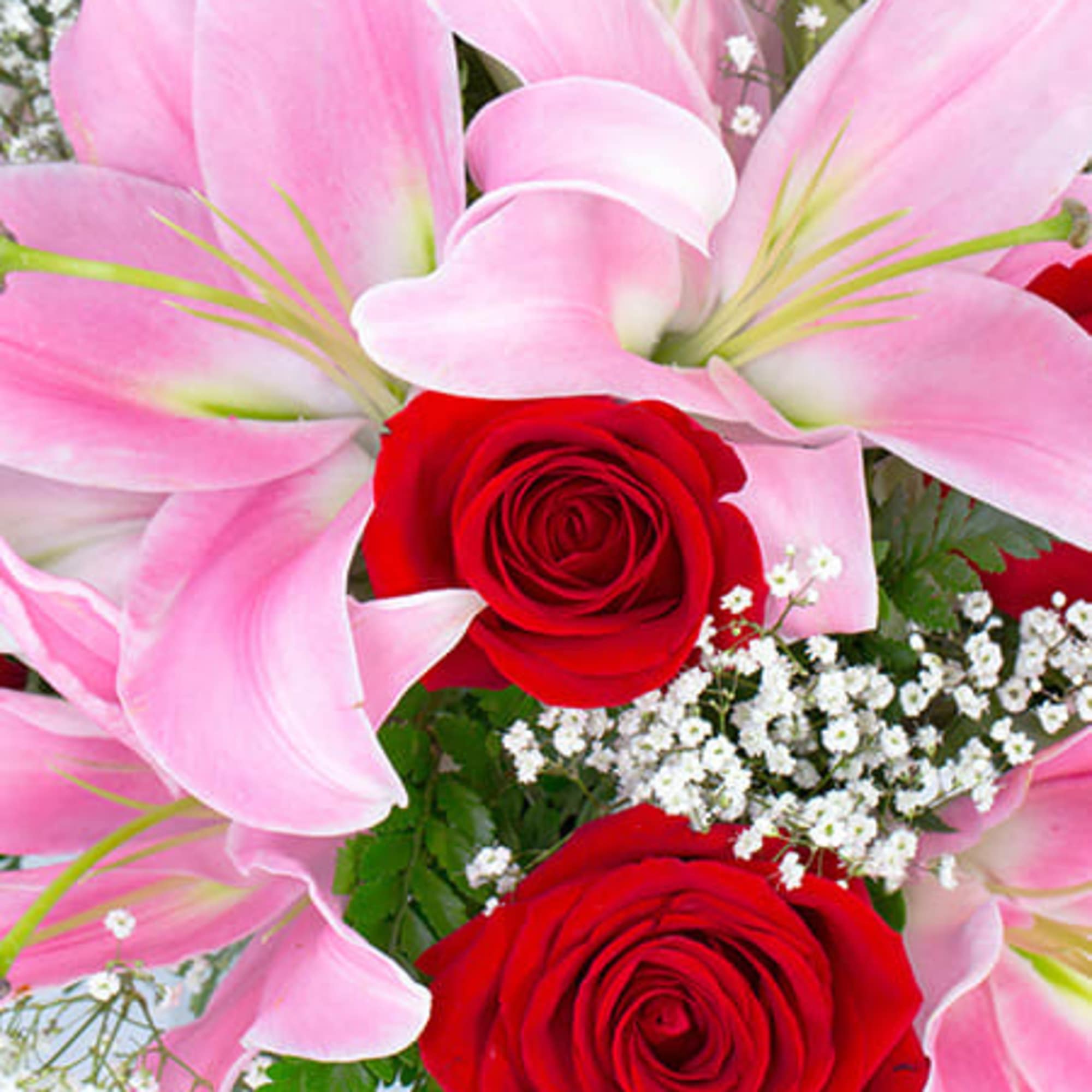 Close-up of pink lilies, red roses, and white filler flowers in a mixed bouquet