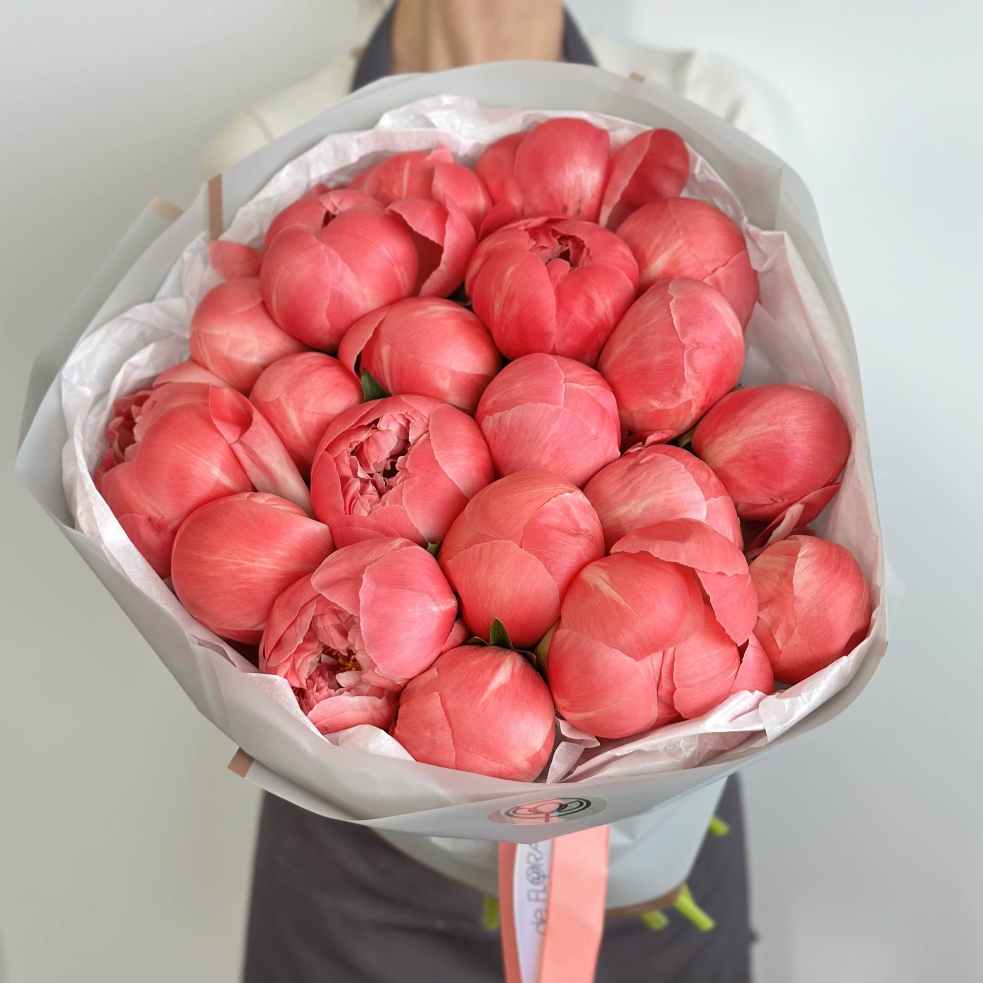 Bouquet of bright pink peonies wrapped in pale paper