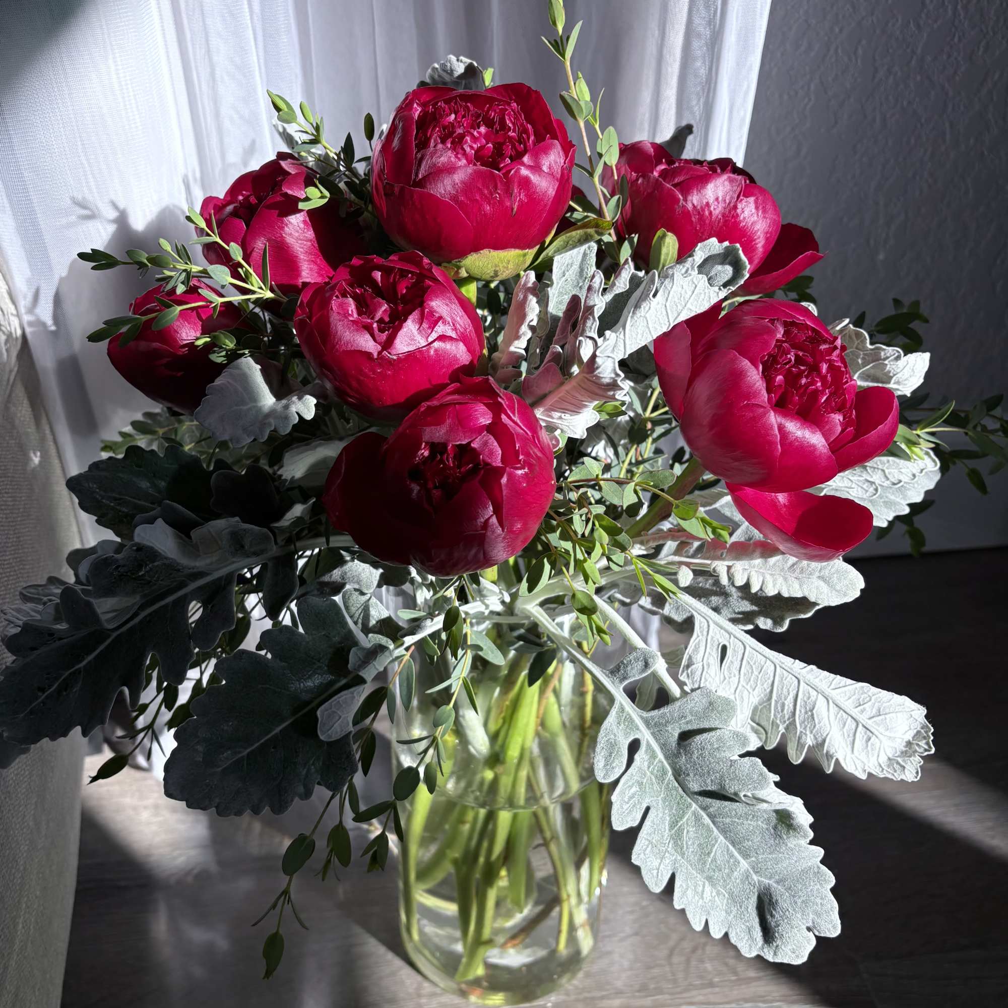 Bouquet of deep pink peonies in a clear glass vase