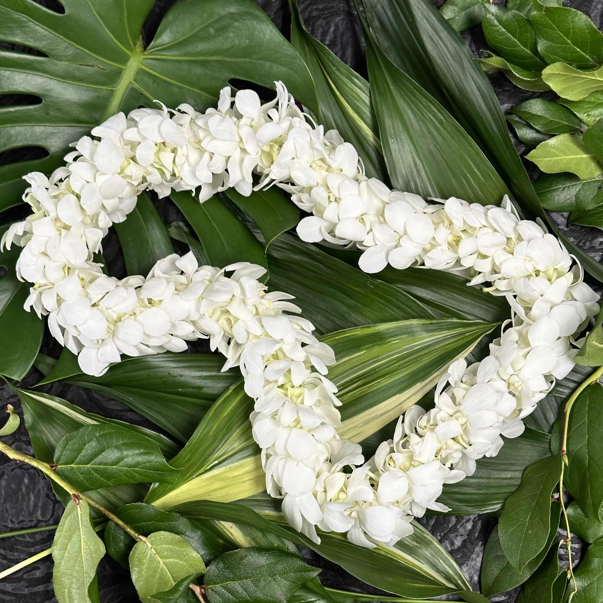 White floral lei on large green leaves