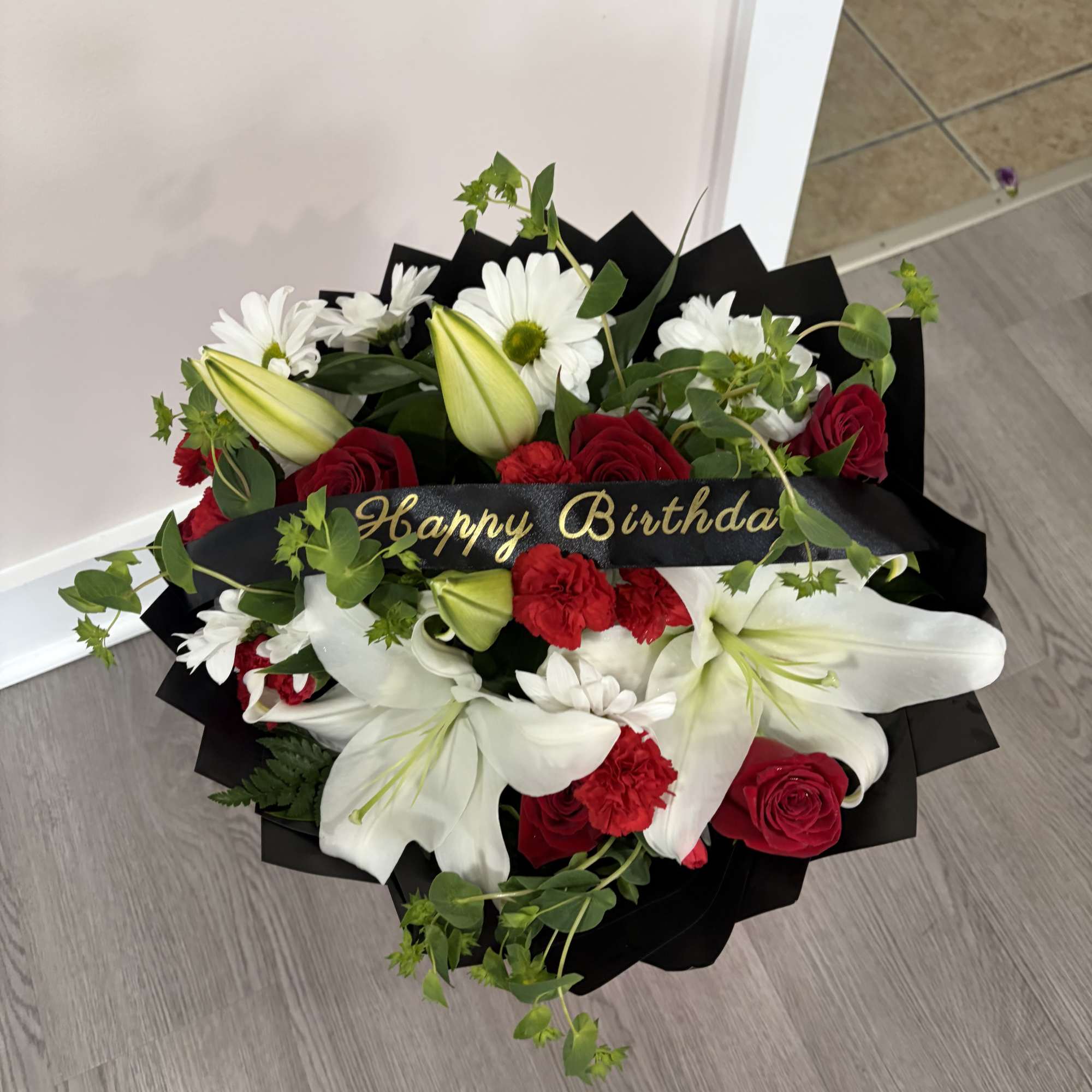A stunning handcrafted bouquet featuring elegant red roses, pure white lilies, vibrant