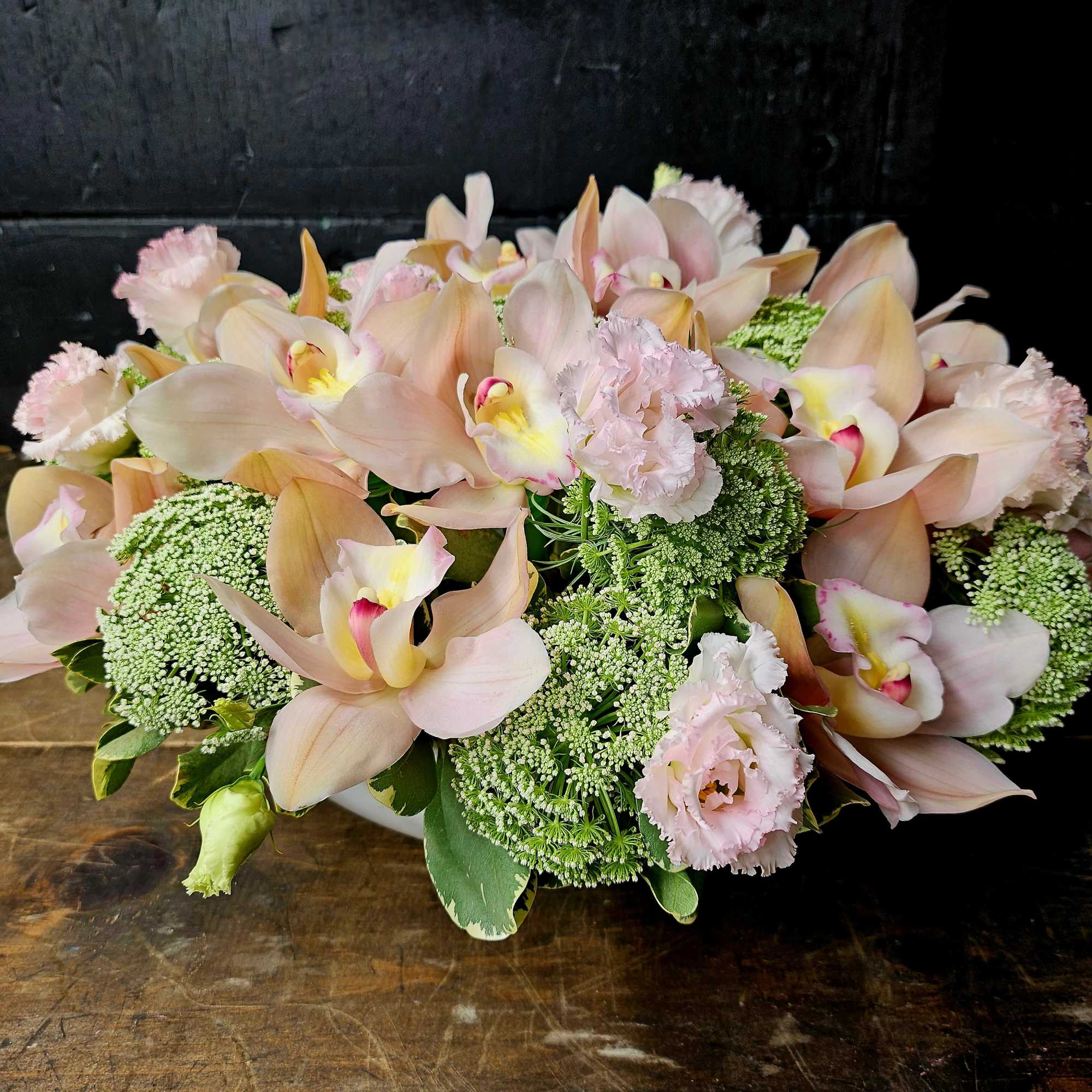 Blush orchids and pale pink carnations in a low arrangement