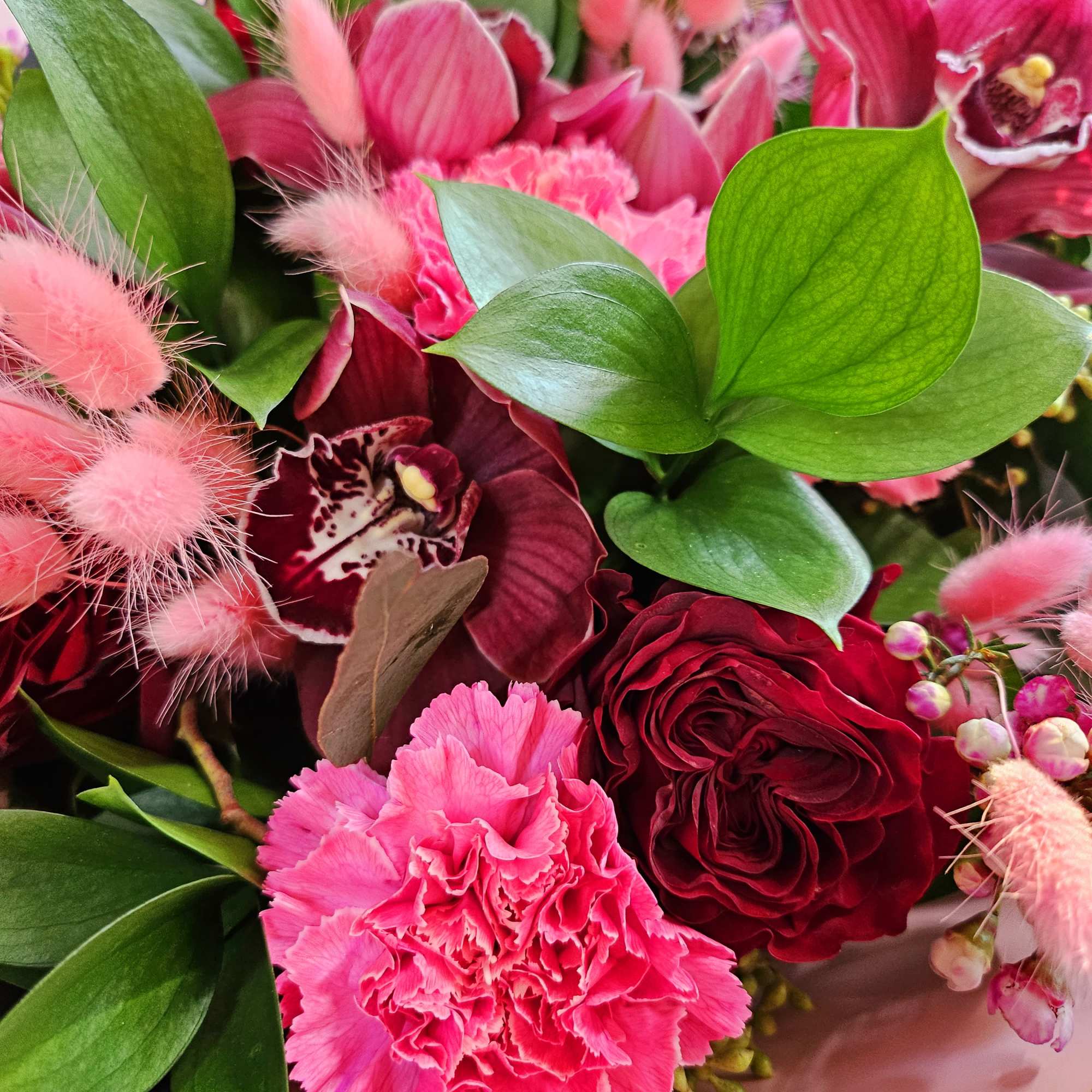 Pink and burgundy bouquet with orchids, roses, and carnations