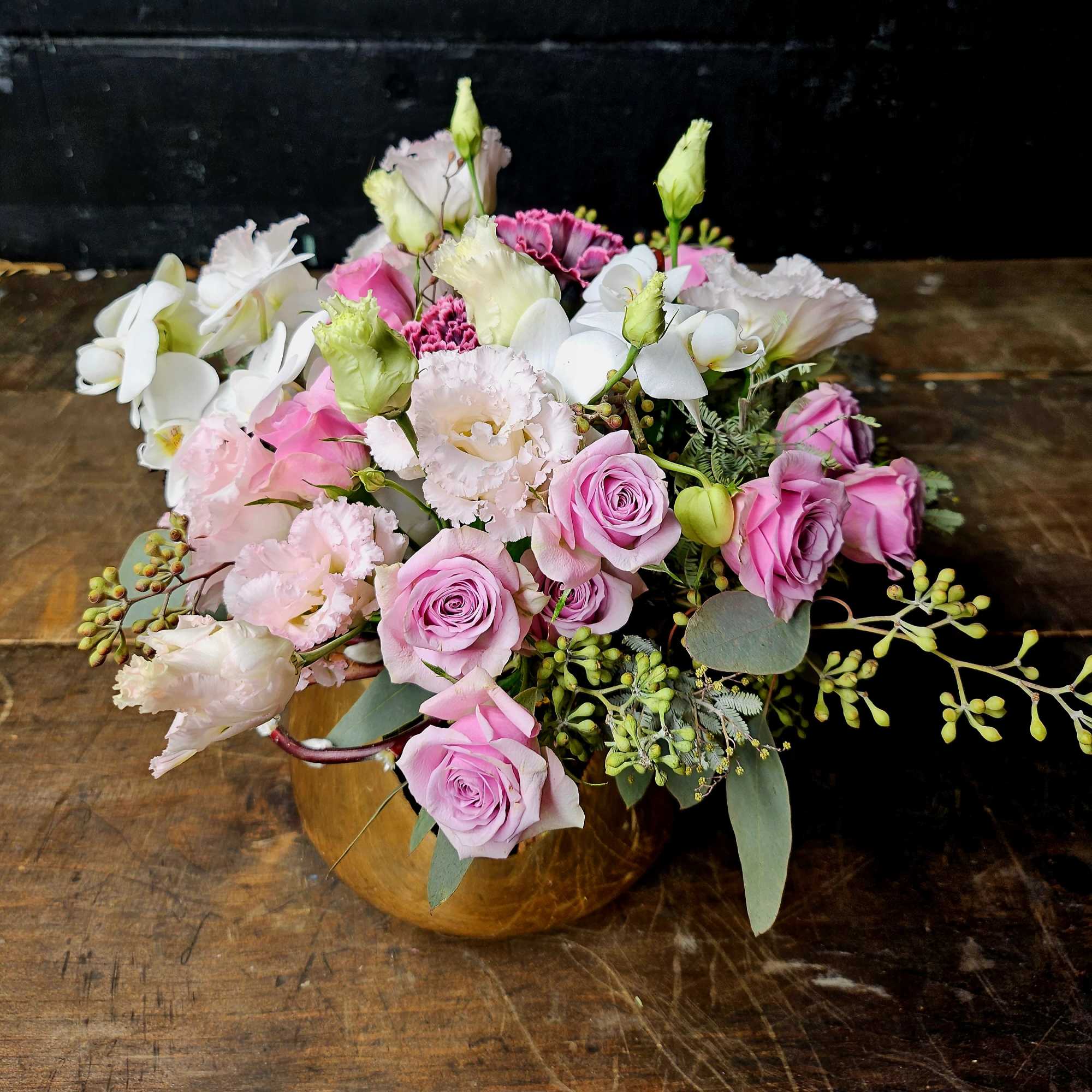 Pink roses and white blooms arranged in a gold vase