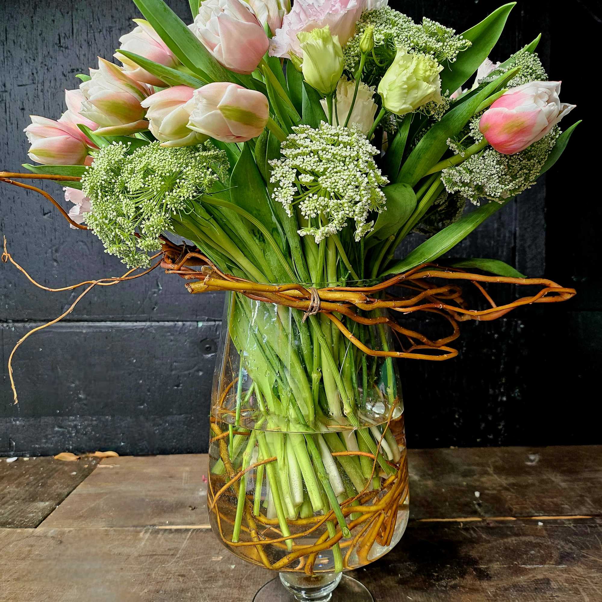Pink and white tulips arranged in a clear glass vase