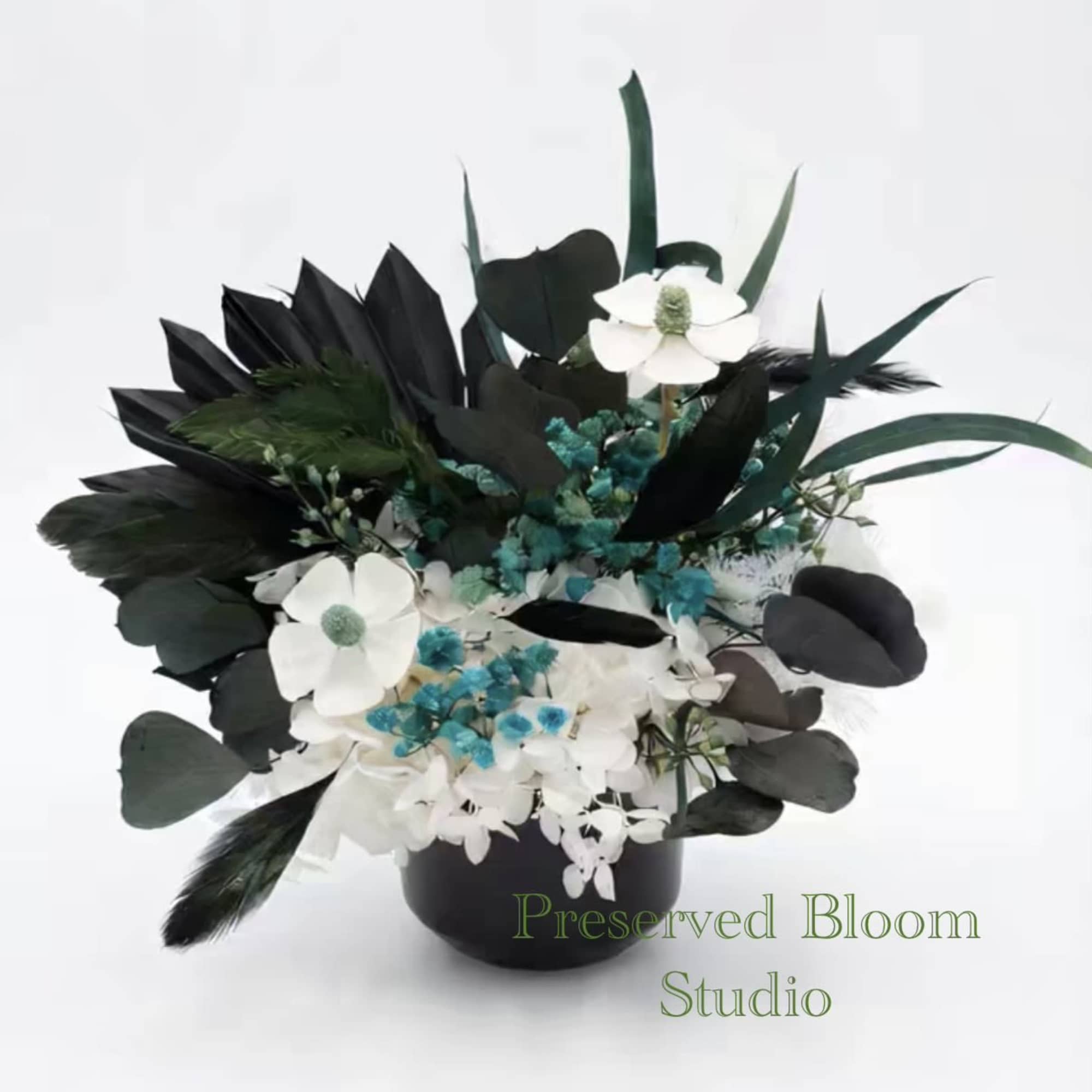 Black and white floral arrangement in a black vase with blue accents