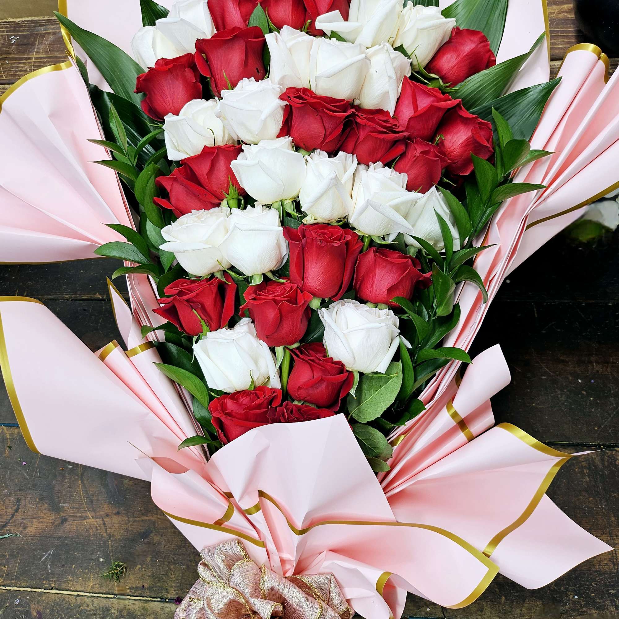 Bouquet of red and white roses wrapped in pink paper