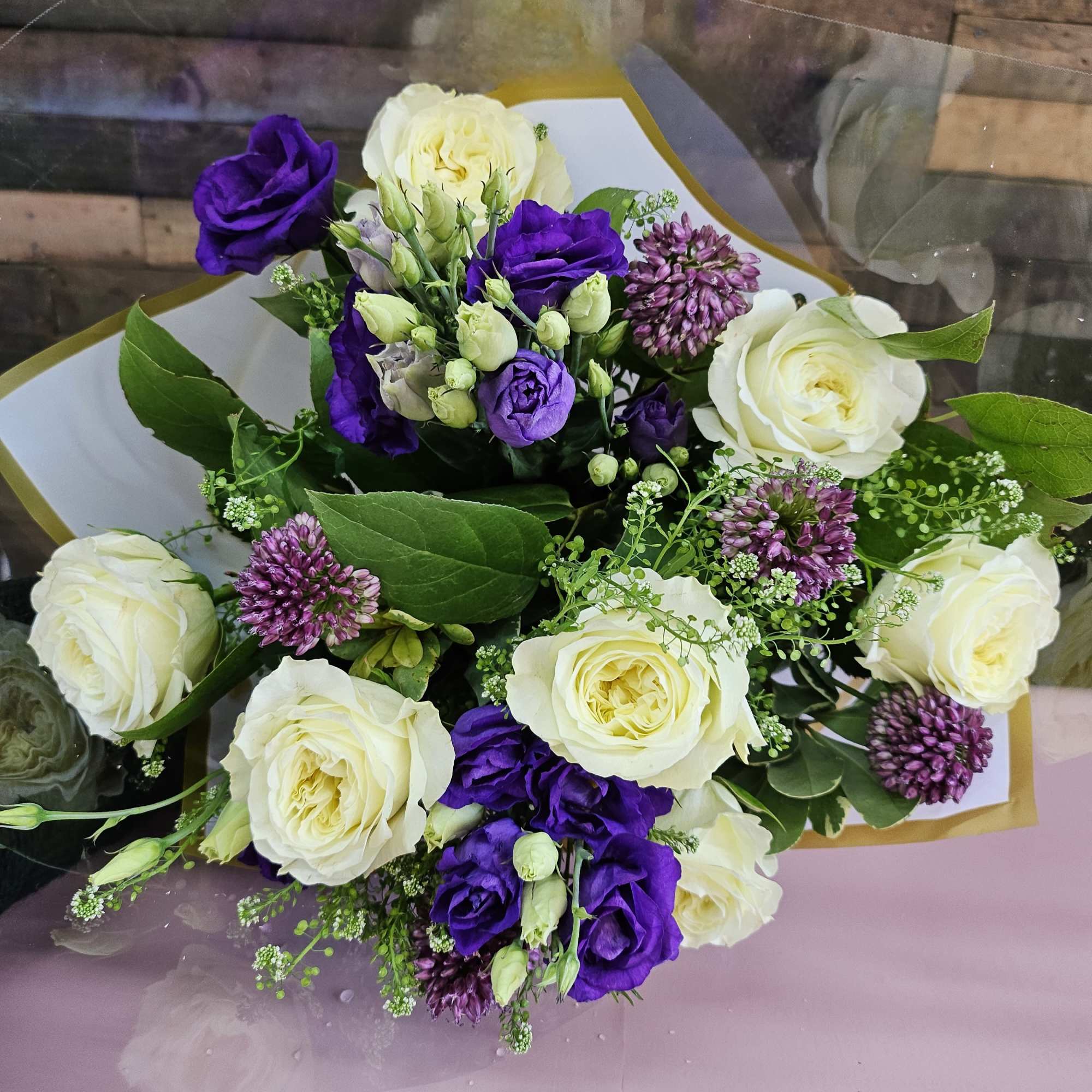 Bouquet of white roses and purple lisianthus wrapped in paper