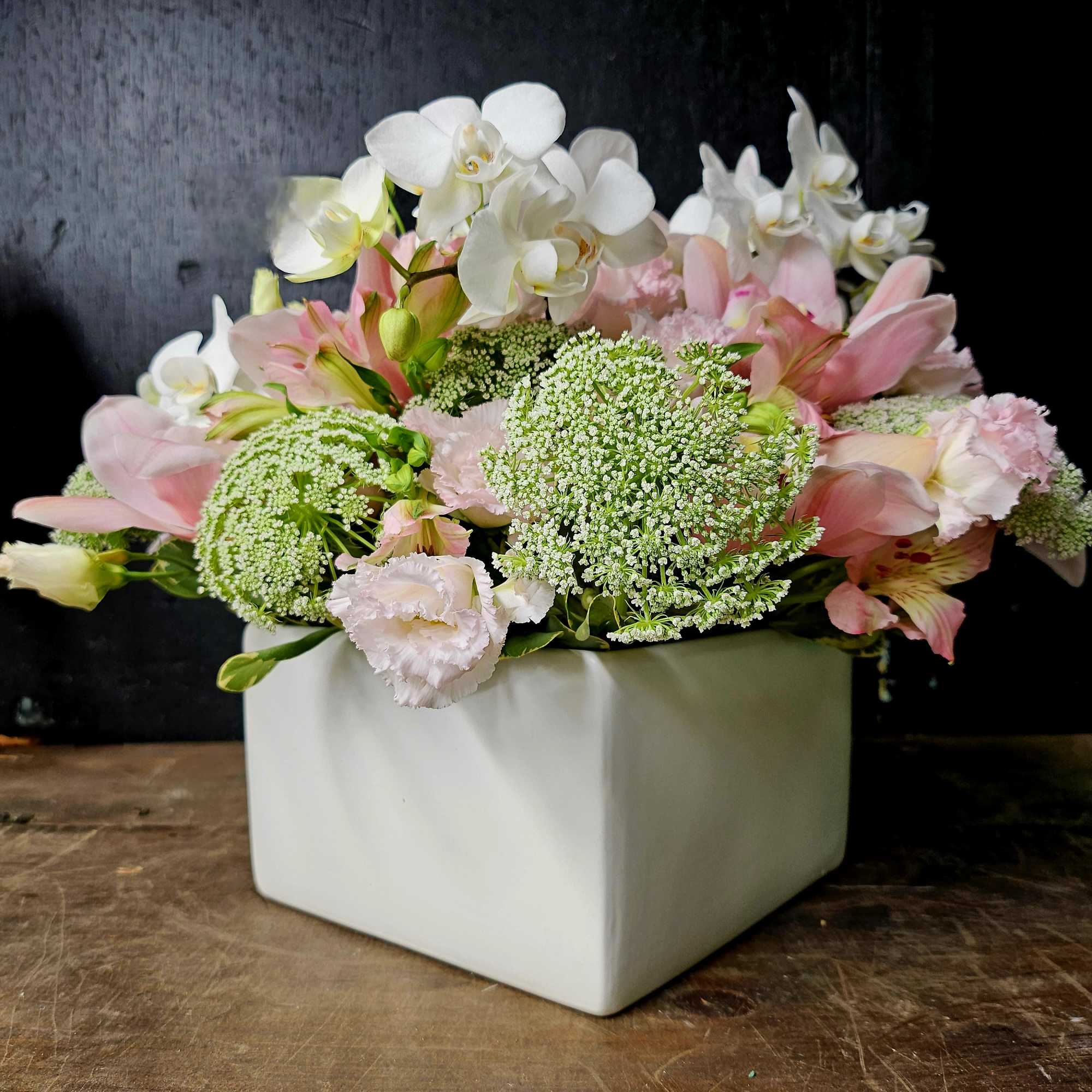 Pink and white floral arrangement in a white square vase
