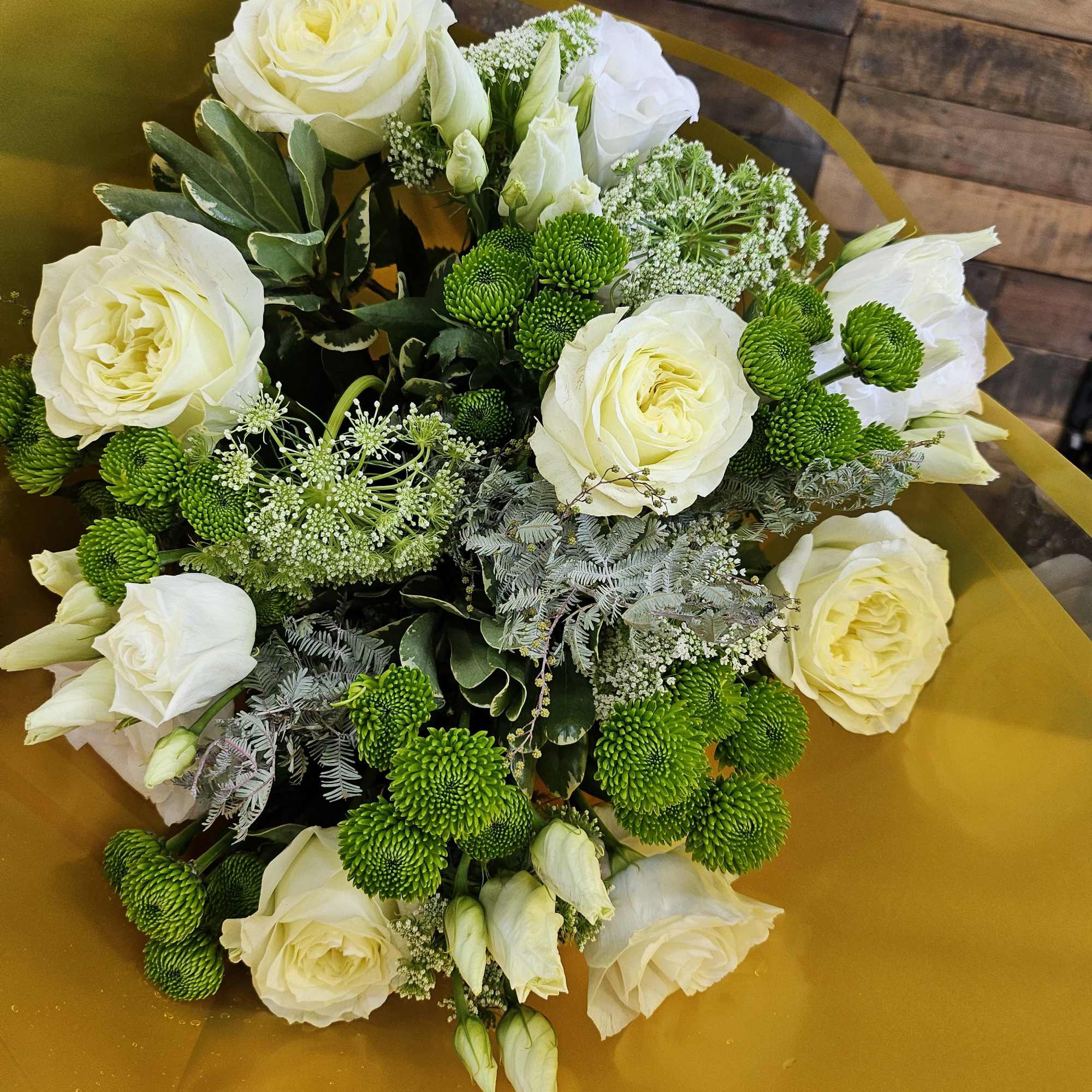 Bouquet of white roses and green button mums wrapped in gold paper
