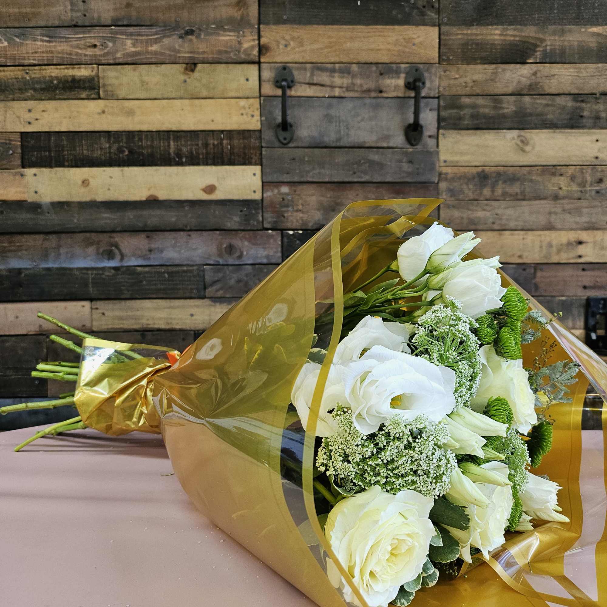 Bouquet of white roses and white lisianthus wrapped in gold paper