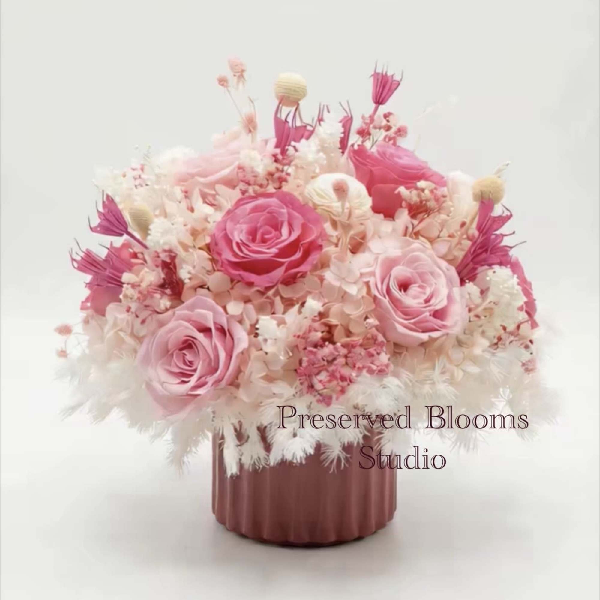 Low pink and white preserved flower arrangement with roses in a mauve ceramic pot