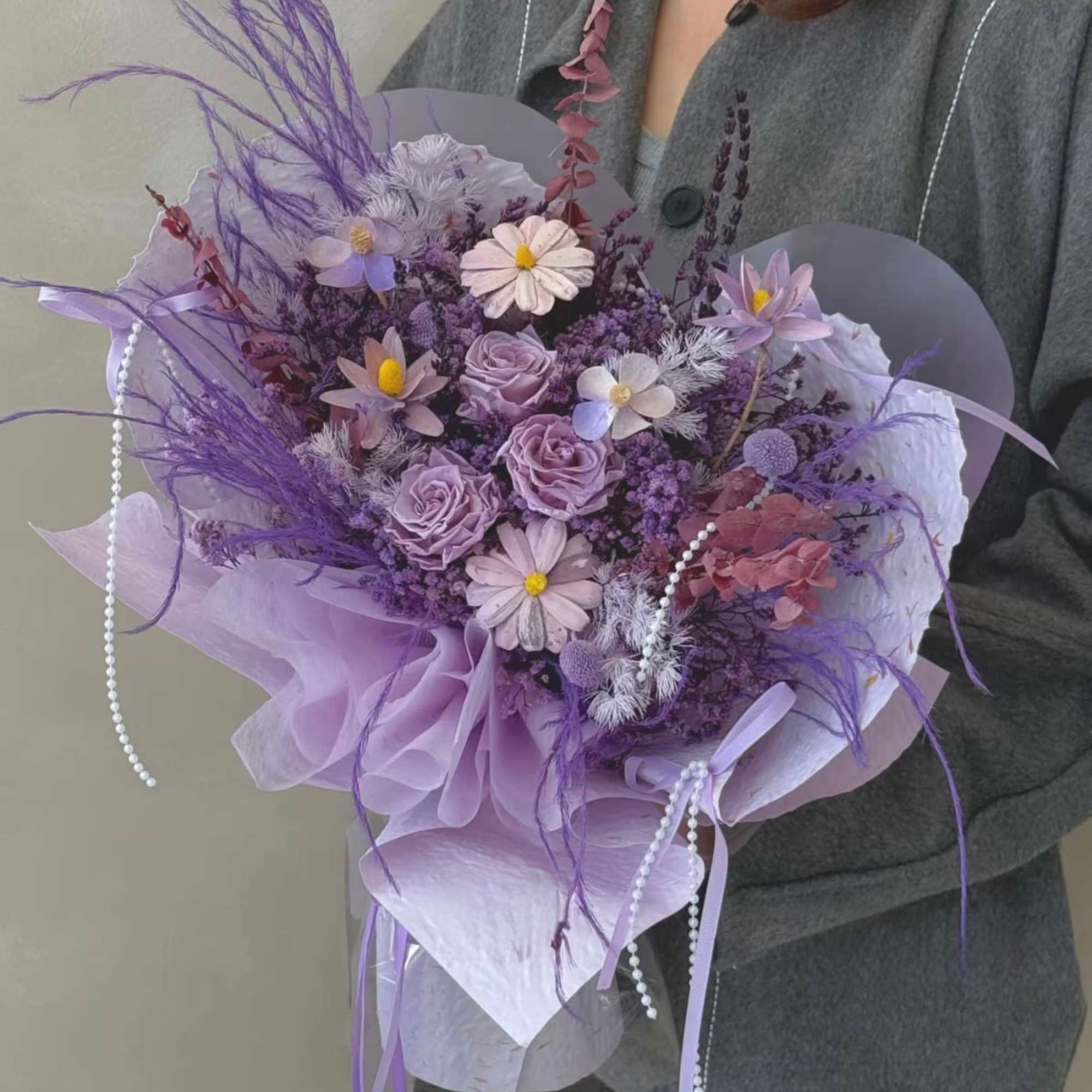 Lavender bouquet with roses and daisy-like blooms wrapped in purple paper