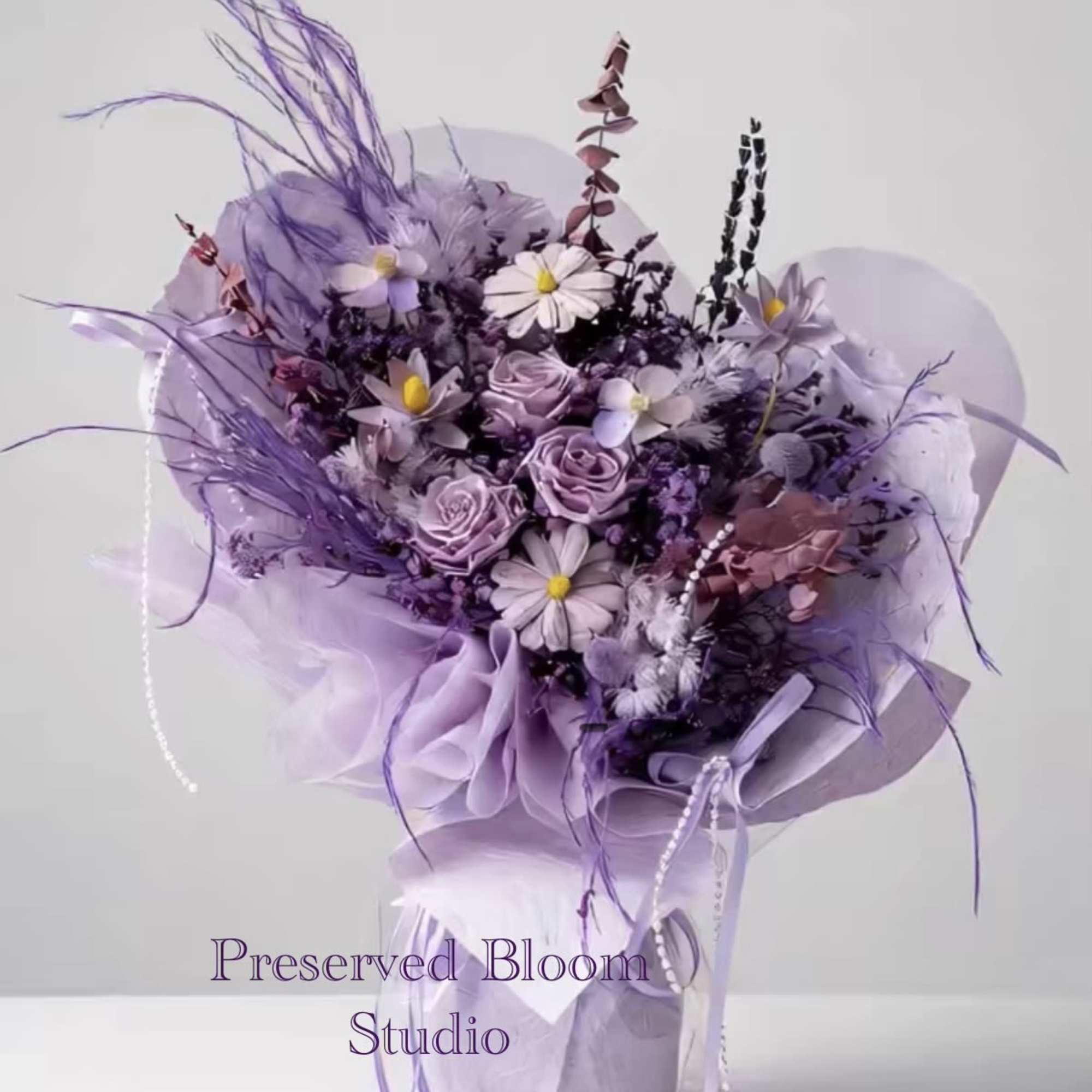 Lavender bouquet with roses and daisy-like flowers wrapped in purple paper