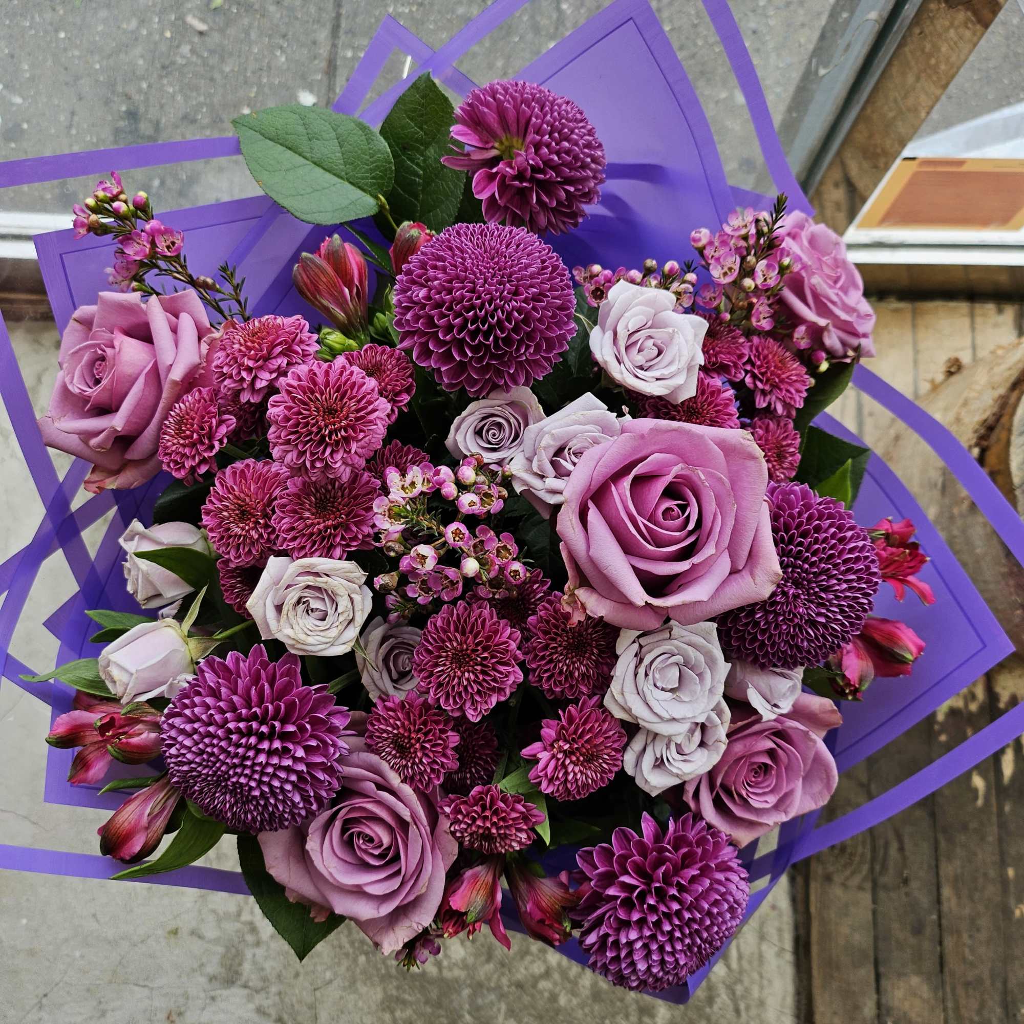Bouquet of purple roses and magenta chrysanthemums wrapped in purple paper