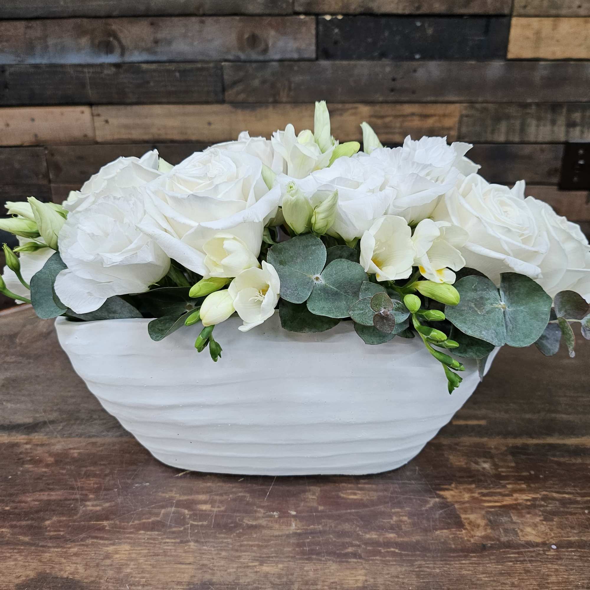 White roses and freesia in a white ceramic bowl