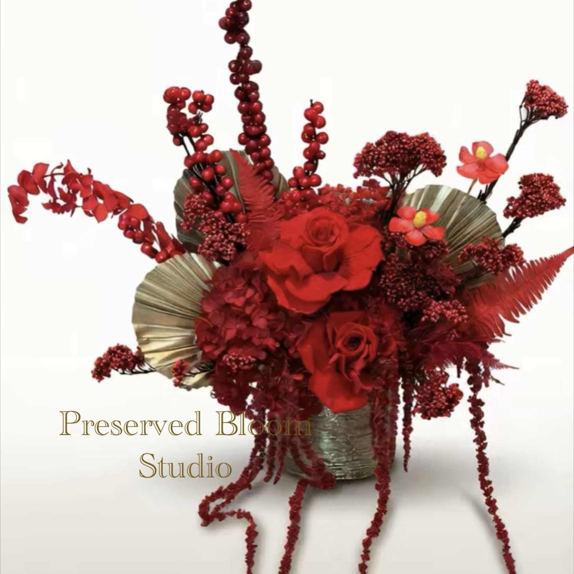 Red rose arrangement in a metallic vase with cascading berry stems