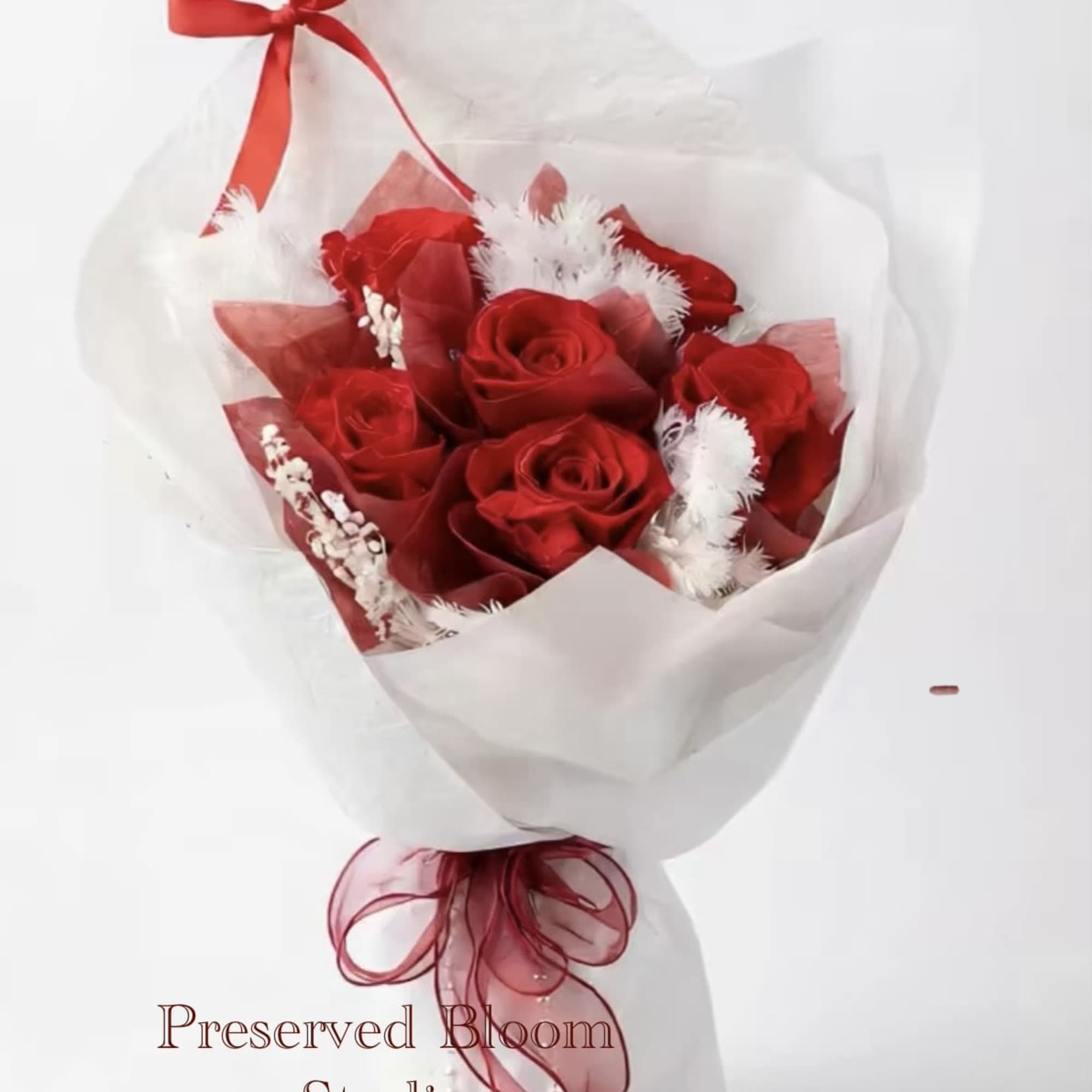 Bouquet of red roses wrapped in white paper with a red ribbon