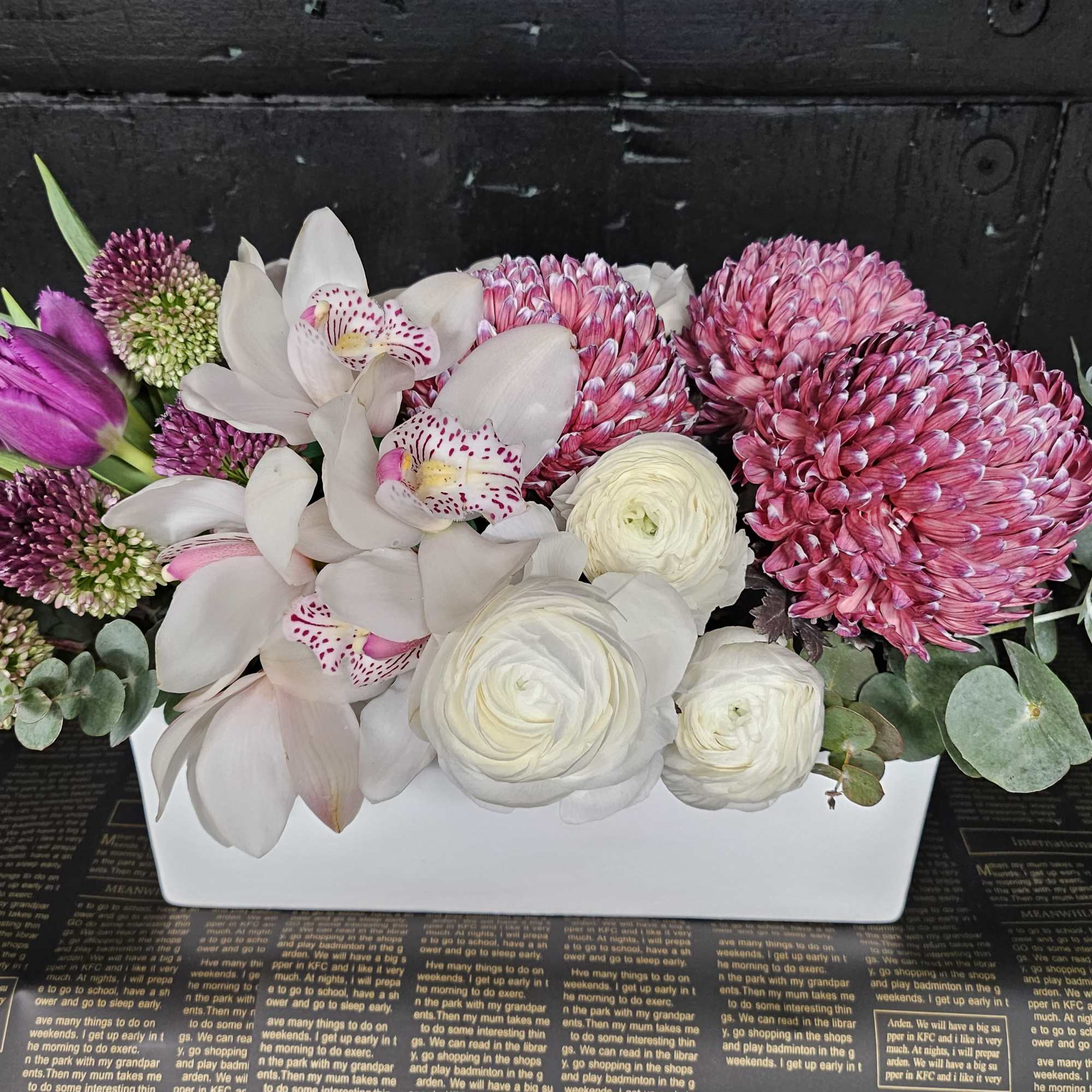 Pink and white flowers arranged in a white rectangular box.