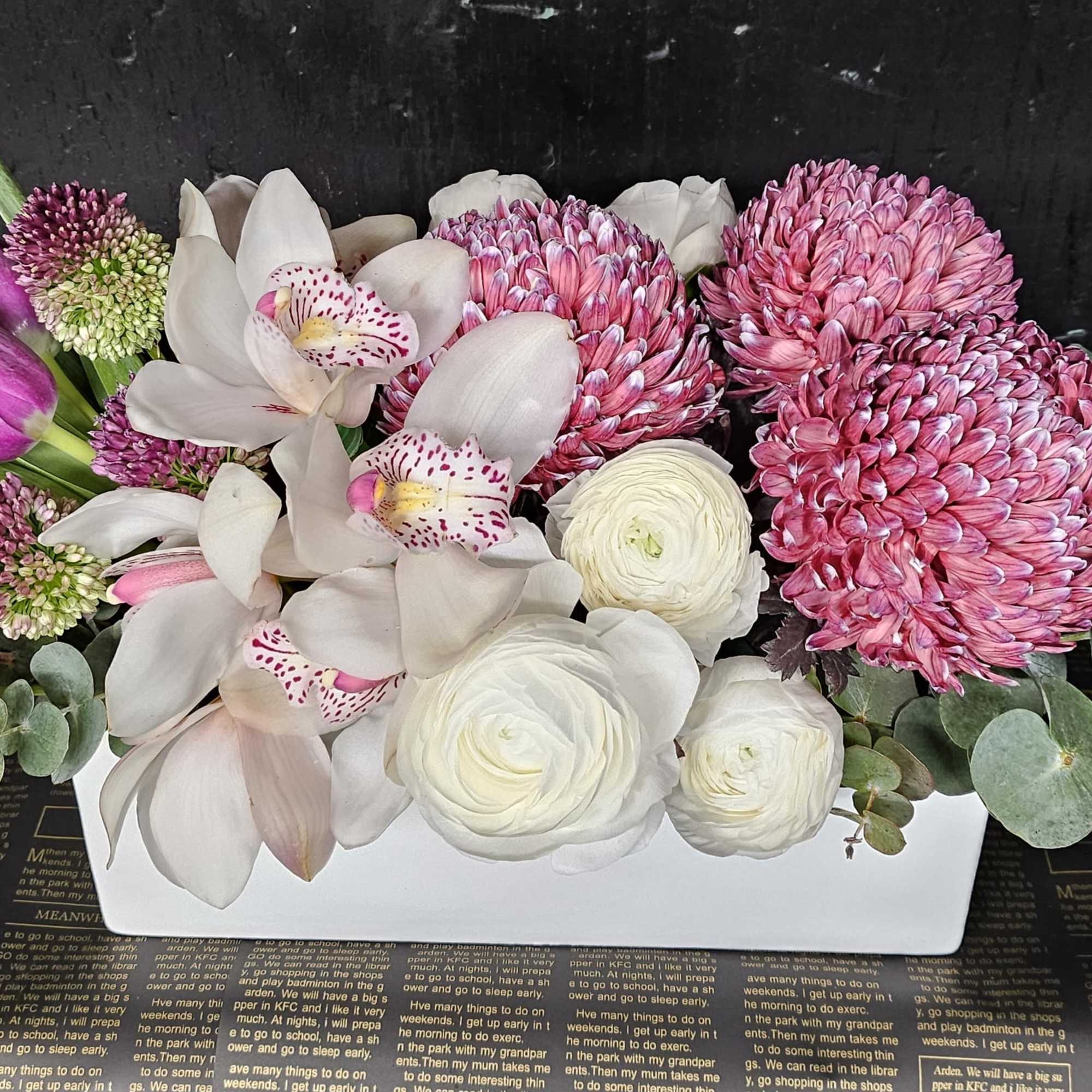 Pink and white floral arrangement in a white rectangular container