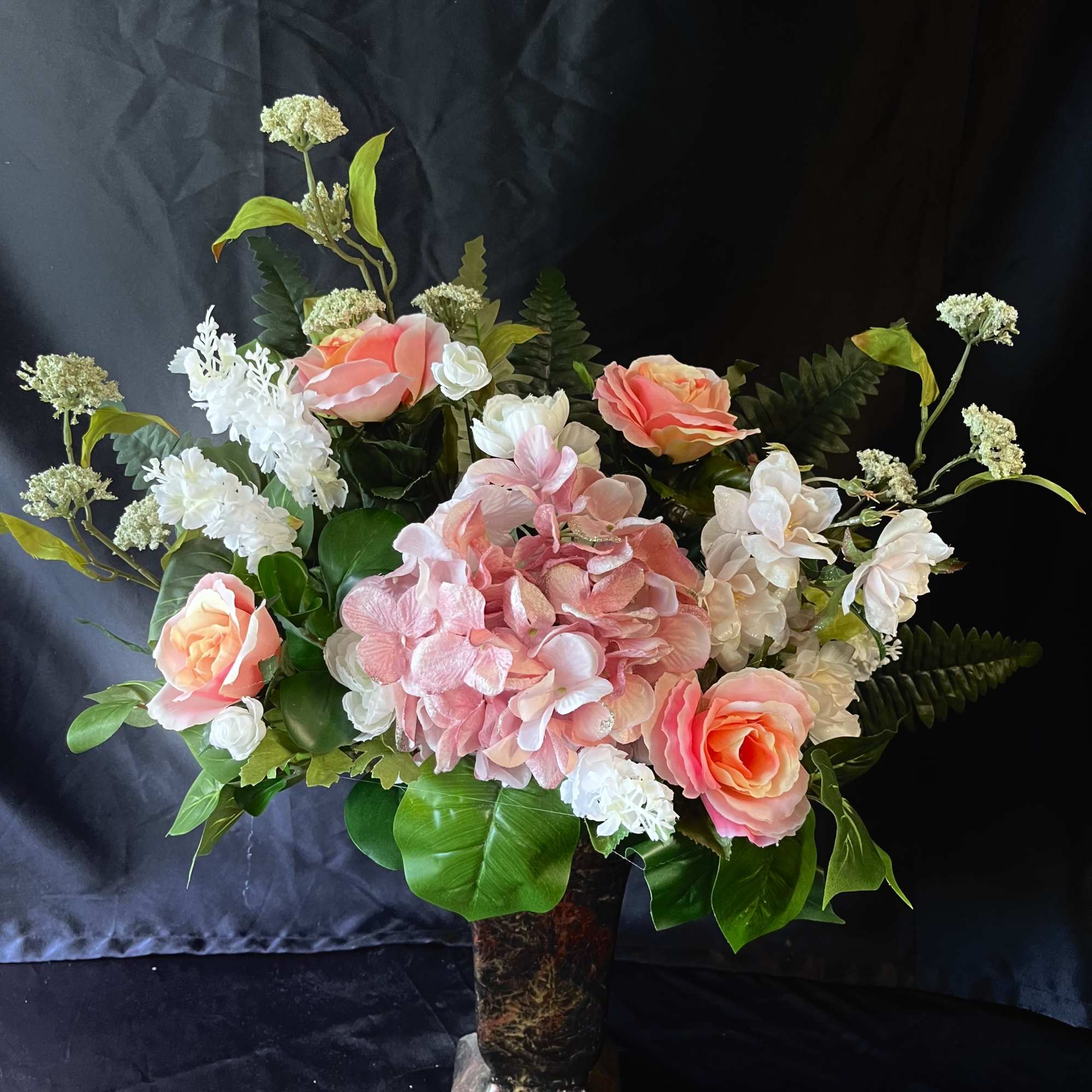 Soft blush hydrangea crowns this romantic bouquet, framed by large pink roses