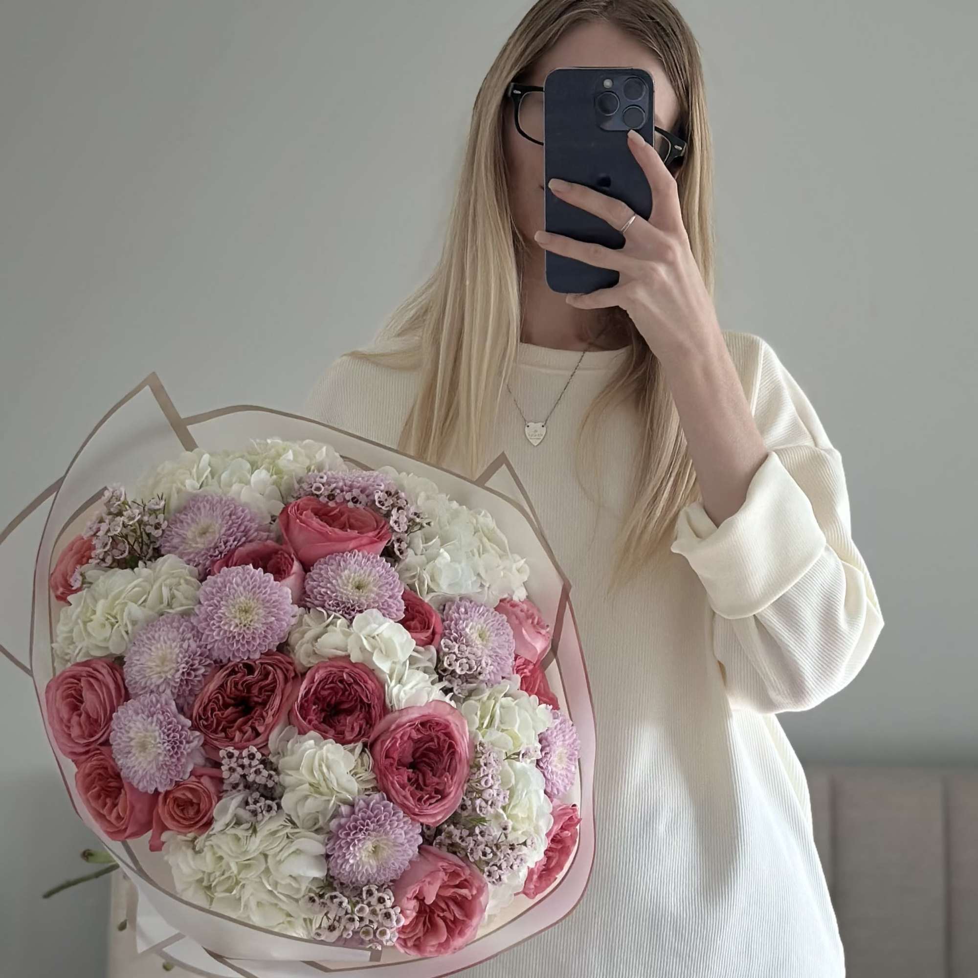 Woman holding a bouquet of pink and white flowers wrapped in paper