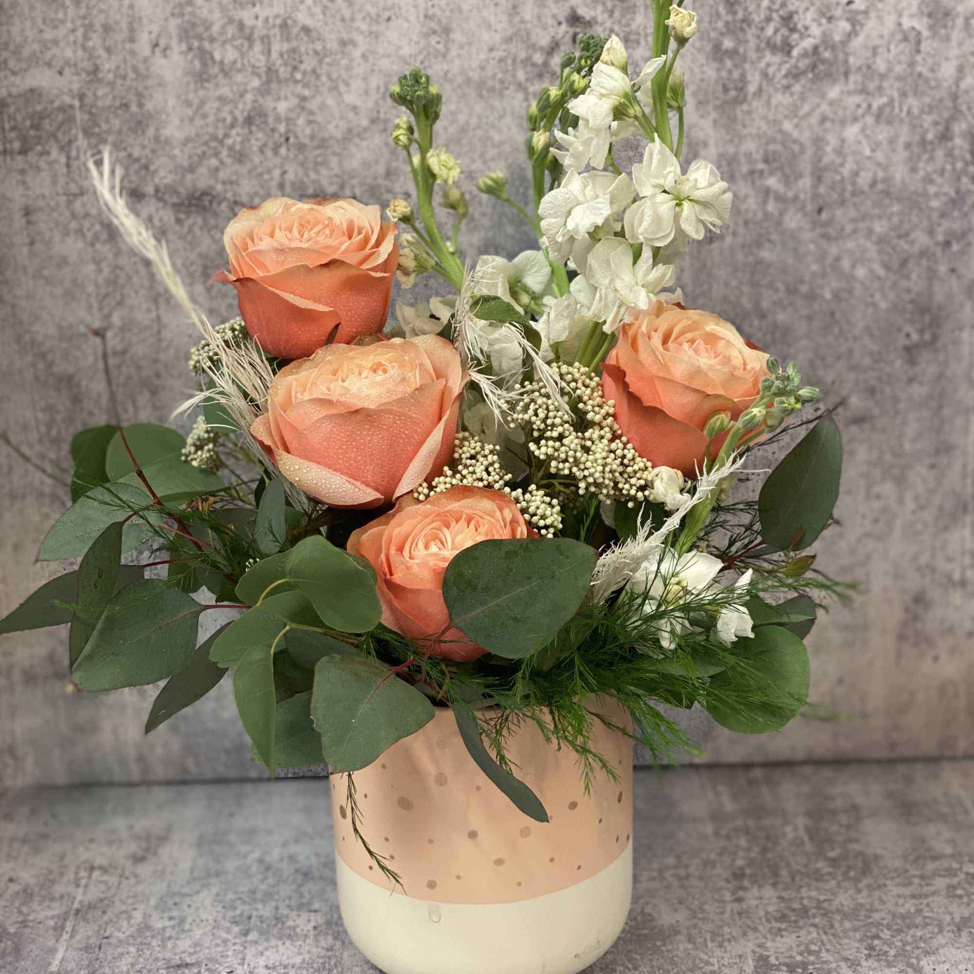 Peach roses and white flowers in a polka-dot vase