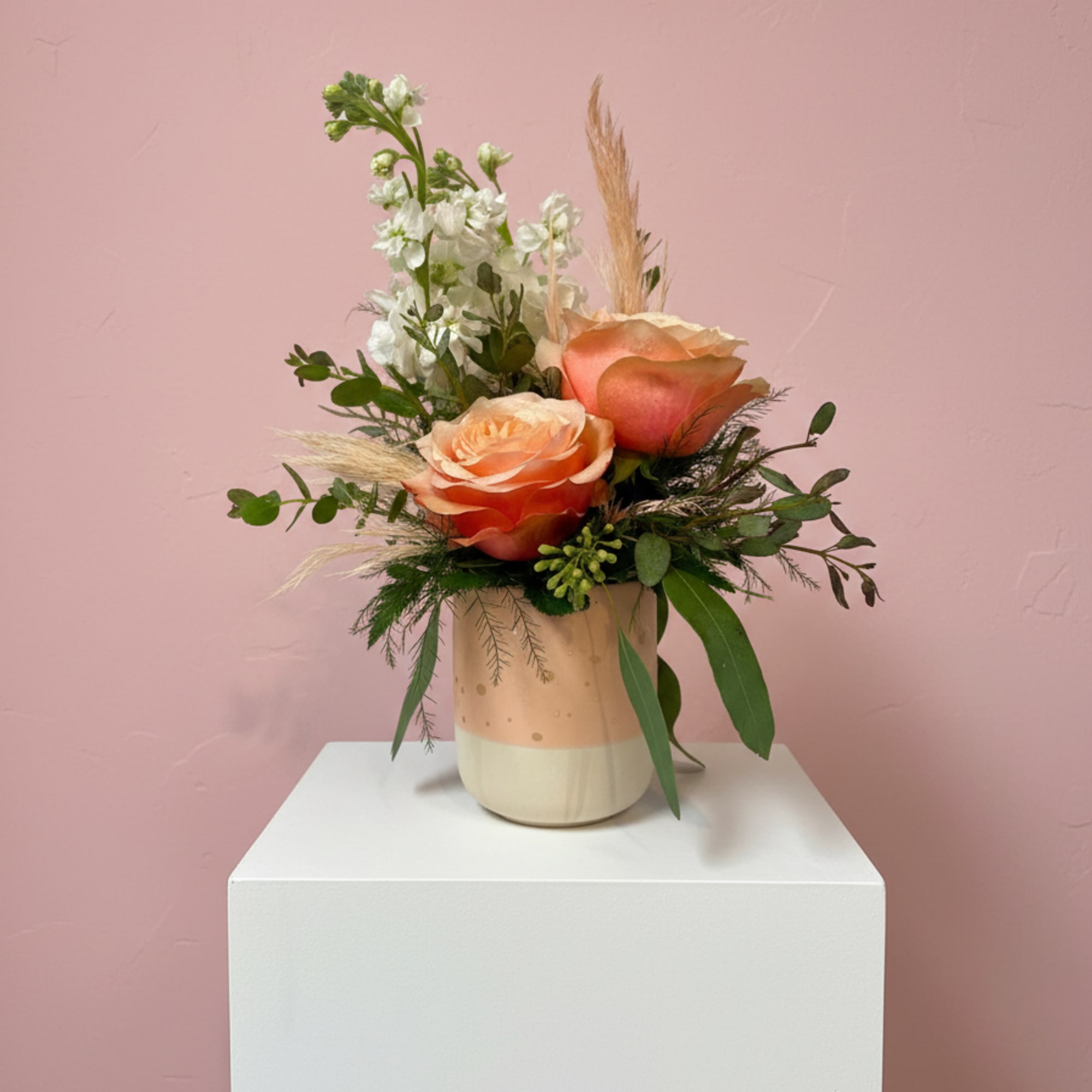 Peach roses in a ceramic vase with white filler flowers