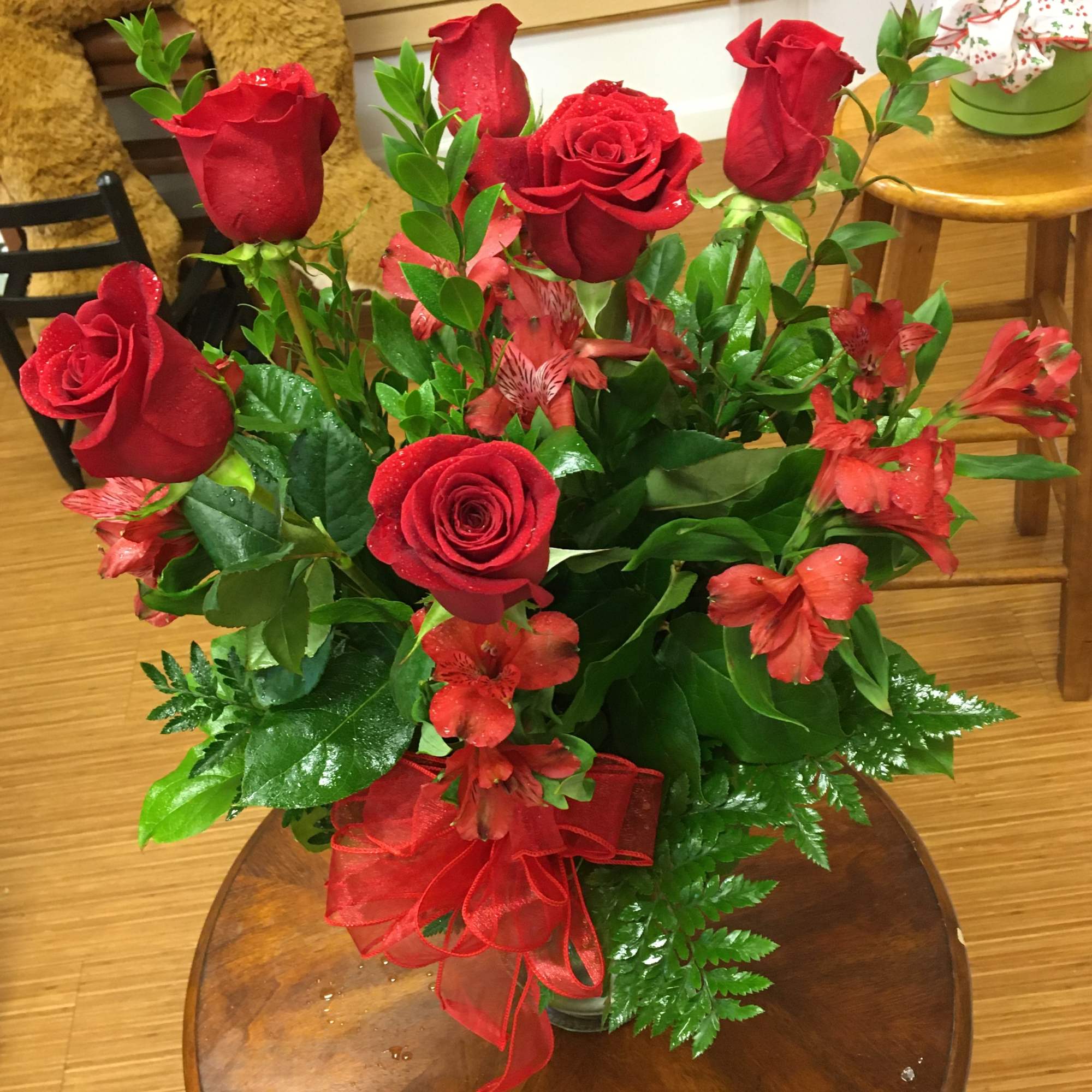 Red roses and red alstroemeria in a vase with a red ribbon