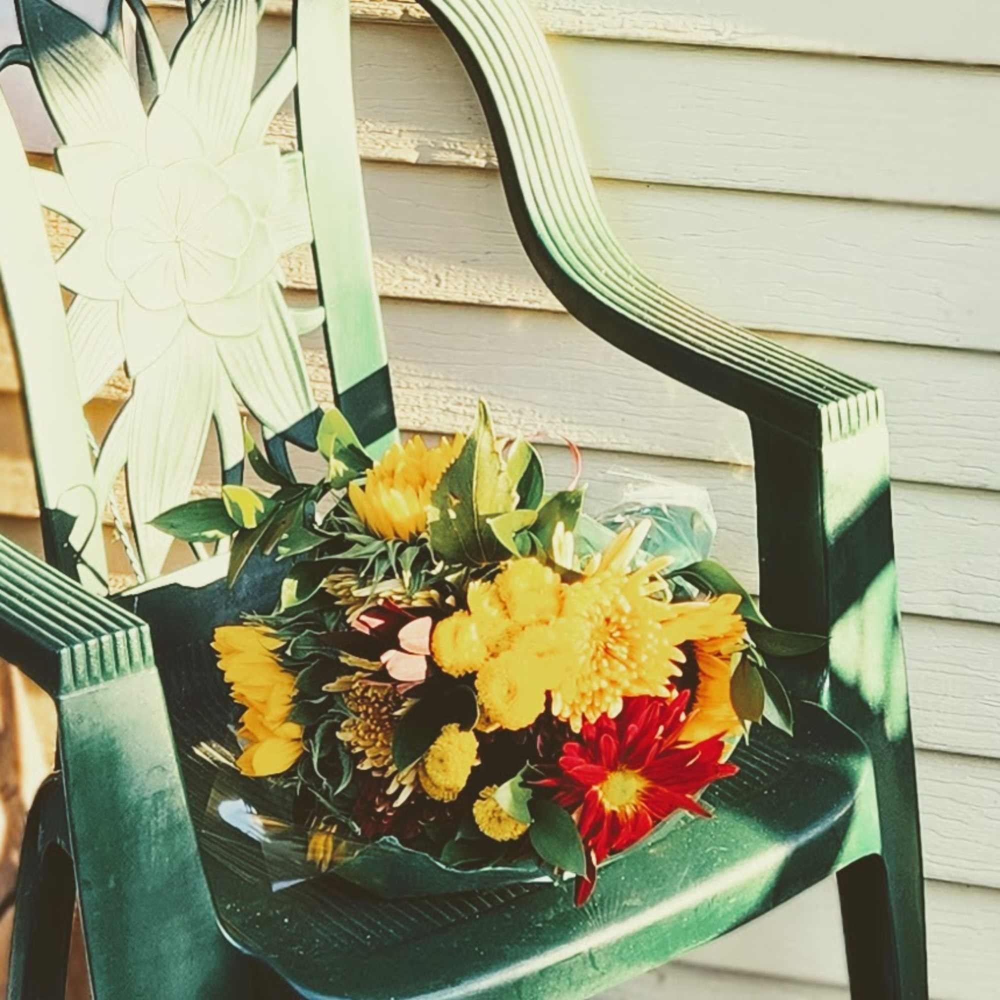 Bouquet of yellow and red flowers on a green chair
