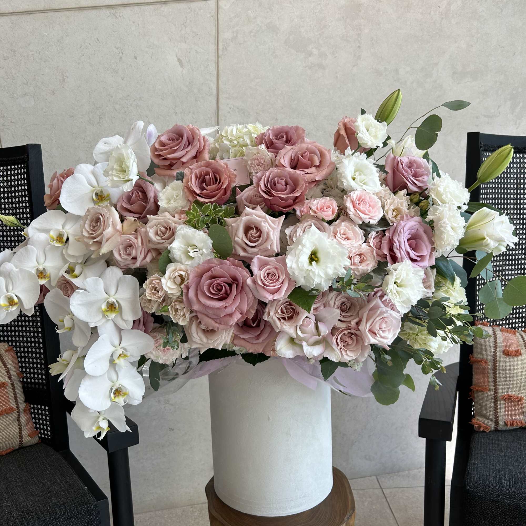 Large pastel bouquet of pink roses and white orchids in a white vase
